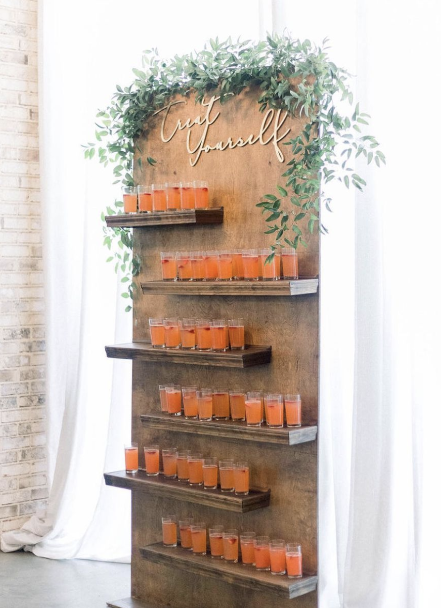 A wooden shelf with drinks and greenery on it.