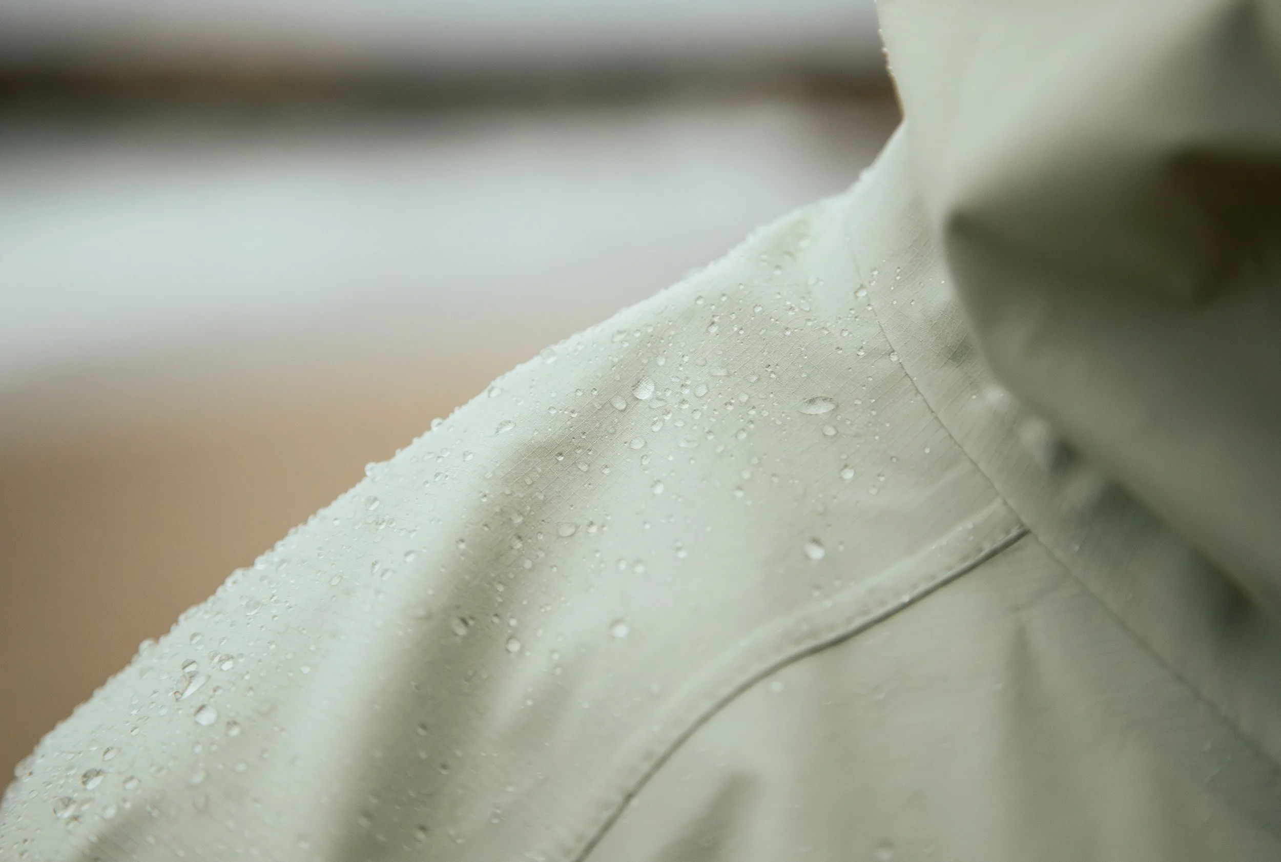 Close-up of a light-colored fabric with water droplets on its surface.