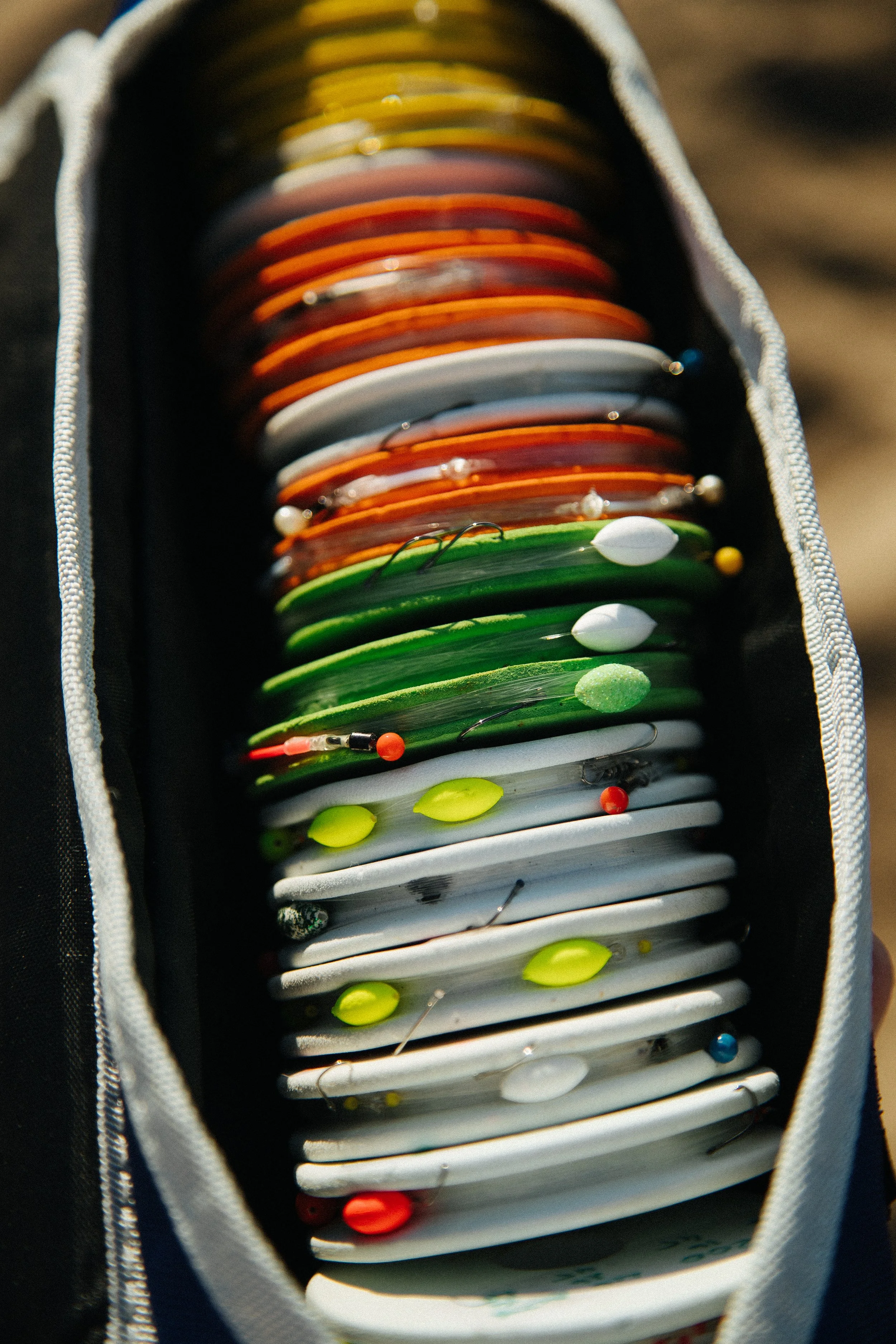 Colorful fishing lures organized in a tackle box, with various bright and reflective surfaces.