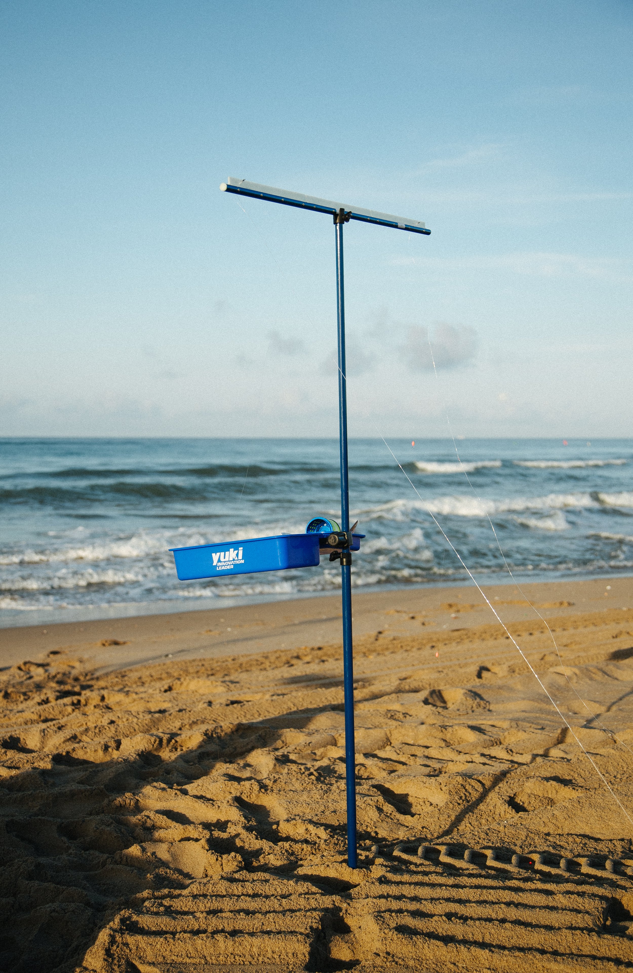A beach scene with a blue Tiki-style device on a pole, used for flying kites, with the ocean and sandy shore in the background.