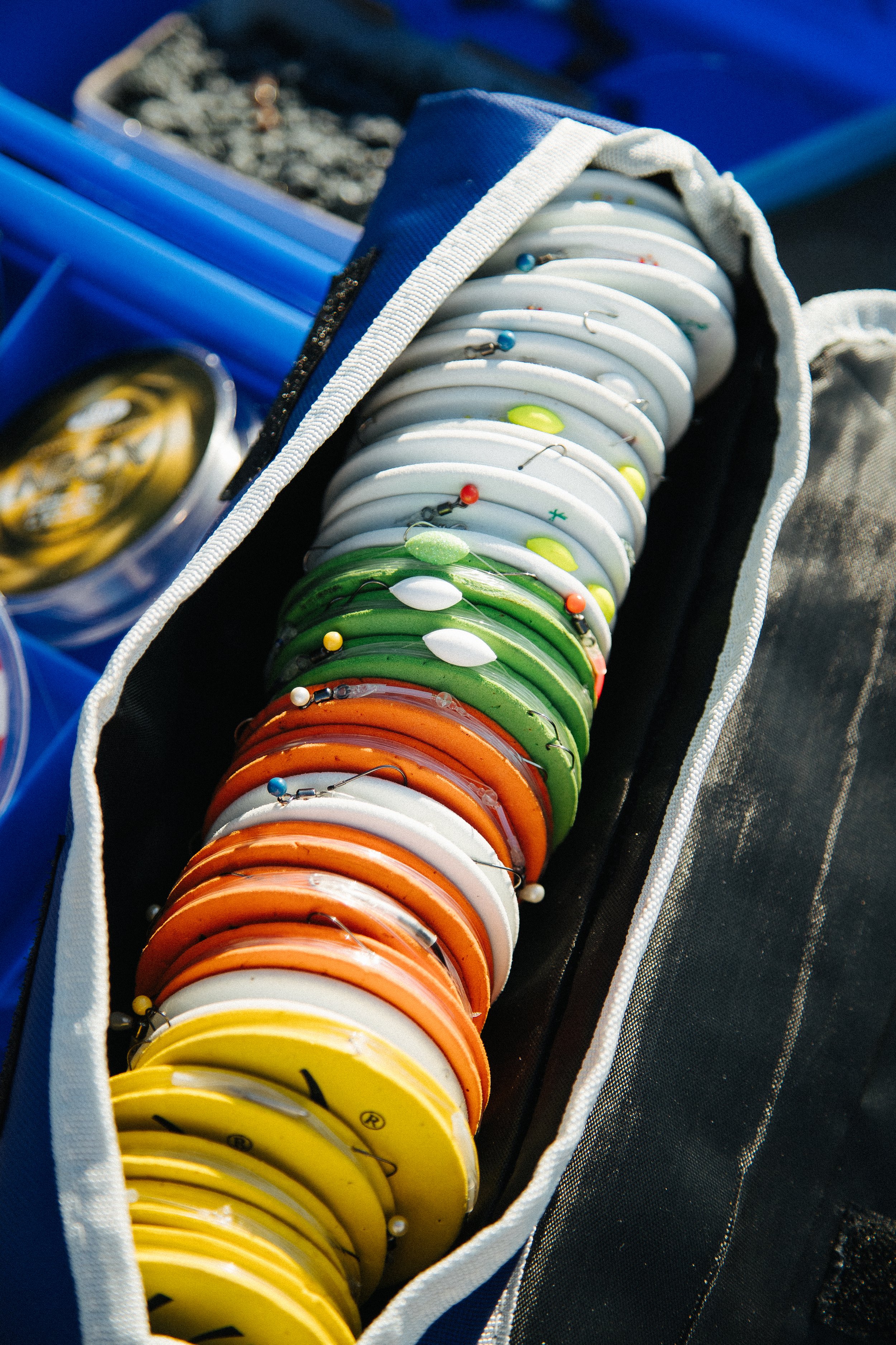 A collection of colorful fishing bobbers, organized by color, inside a fishing gear bag.