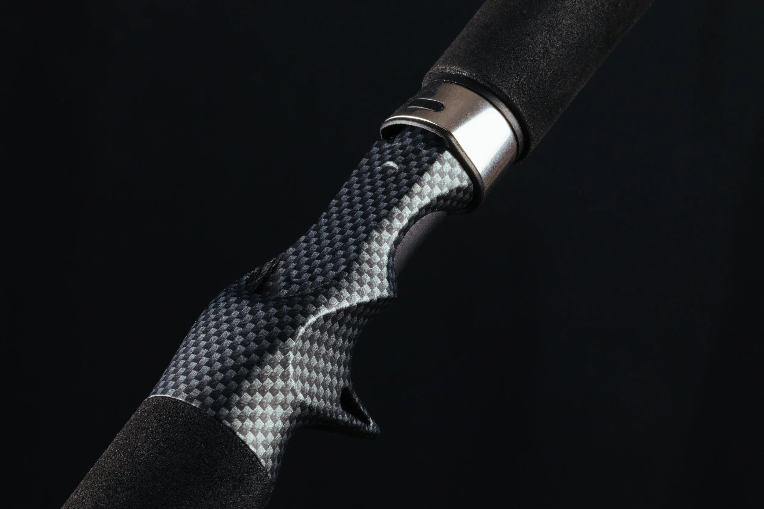 Close-up of a bicycle handlebar and grip with carbon fiber texture against a black background.