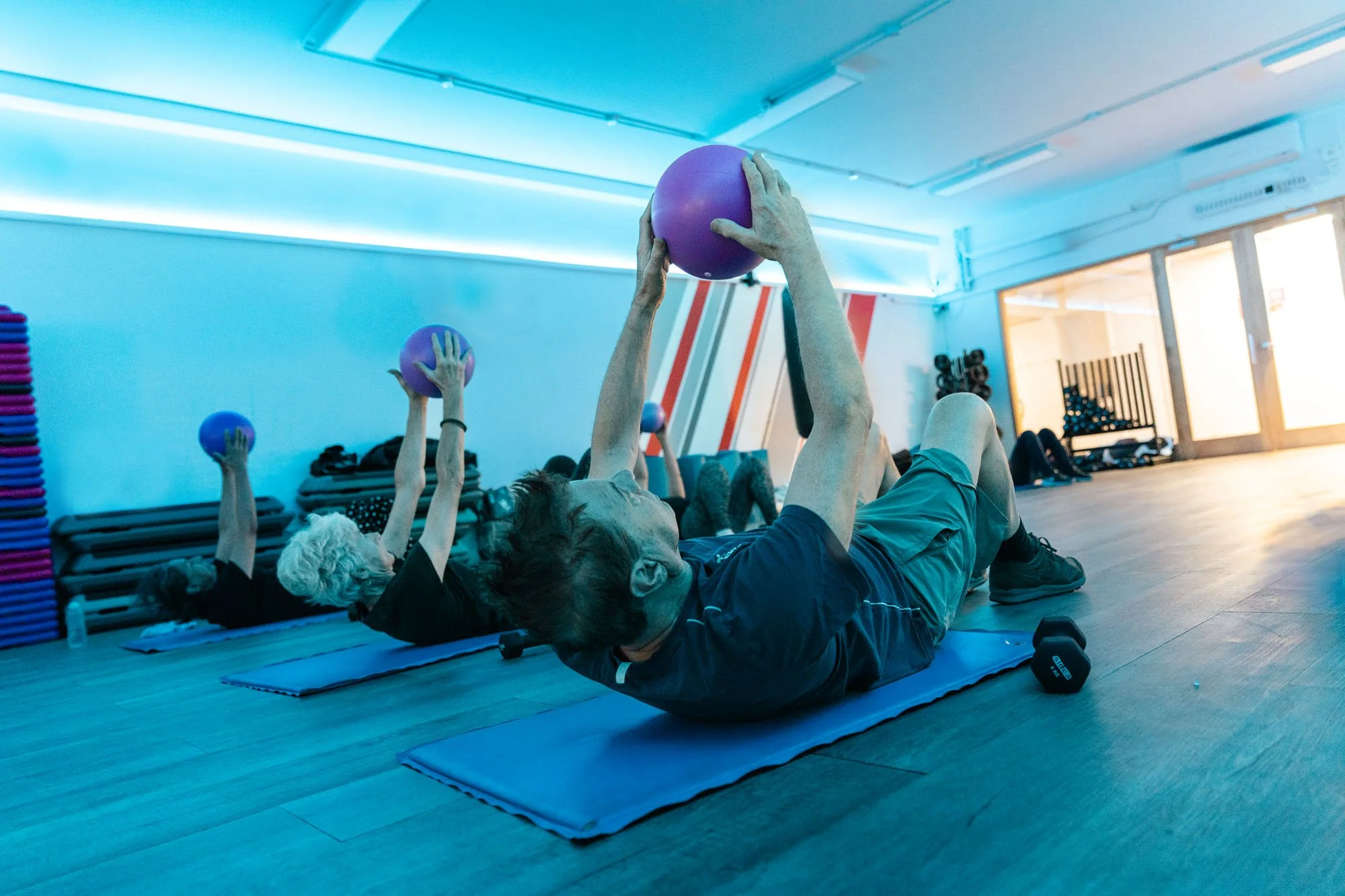 Two women doing forearm plank exercises on a gym floor. Two people working out together for better results. 