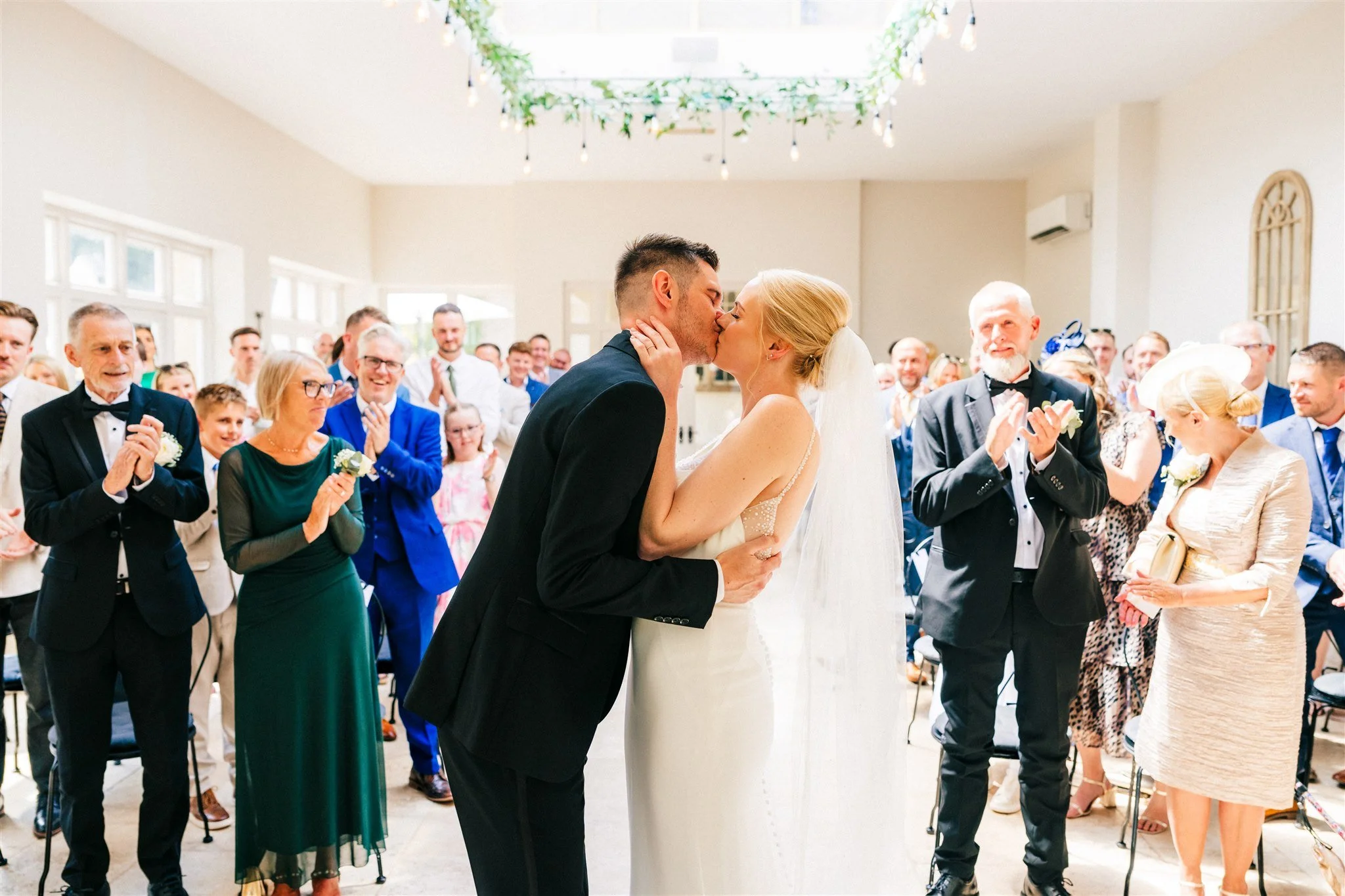 Bride and groom kiss during their wedding ceremony at Woodbury Hall in the Orangery