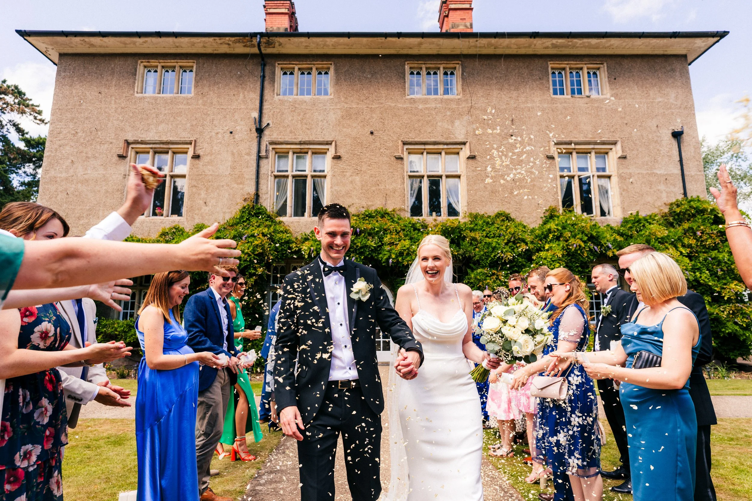 WOODBOROUGH HALL WEDDING PHOTOGRAPHER - bride and groom getting covered in confetti in front of Woodborough Hall
