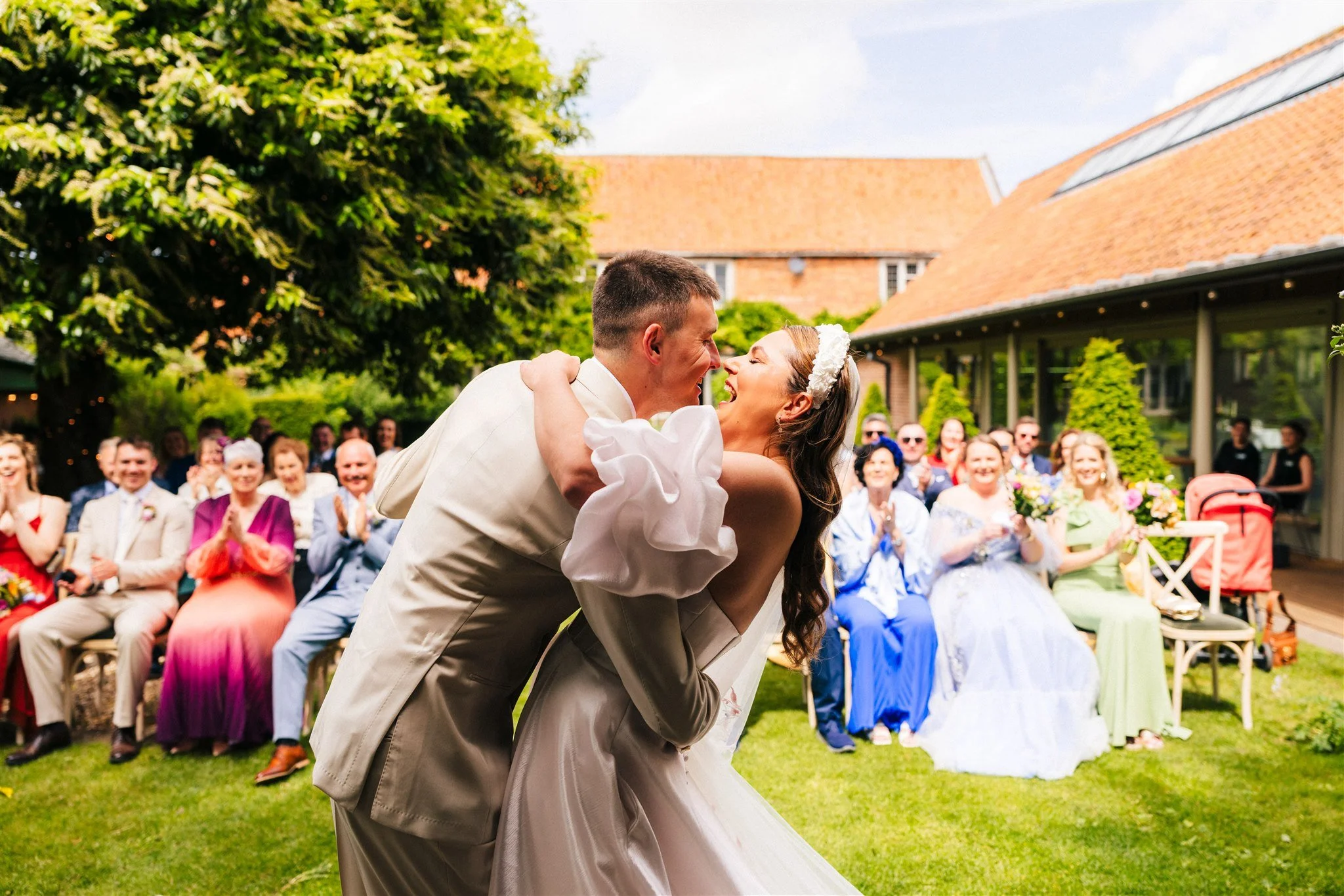 Doddington Hall Wedding Venue Guide - bride and groom kiss during their outdoor wedding ceremony