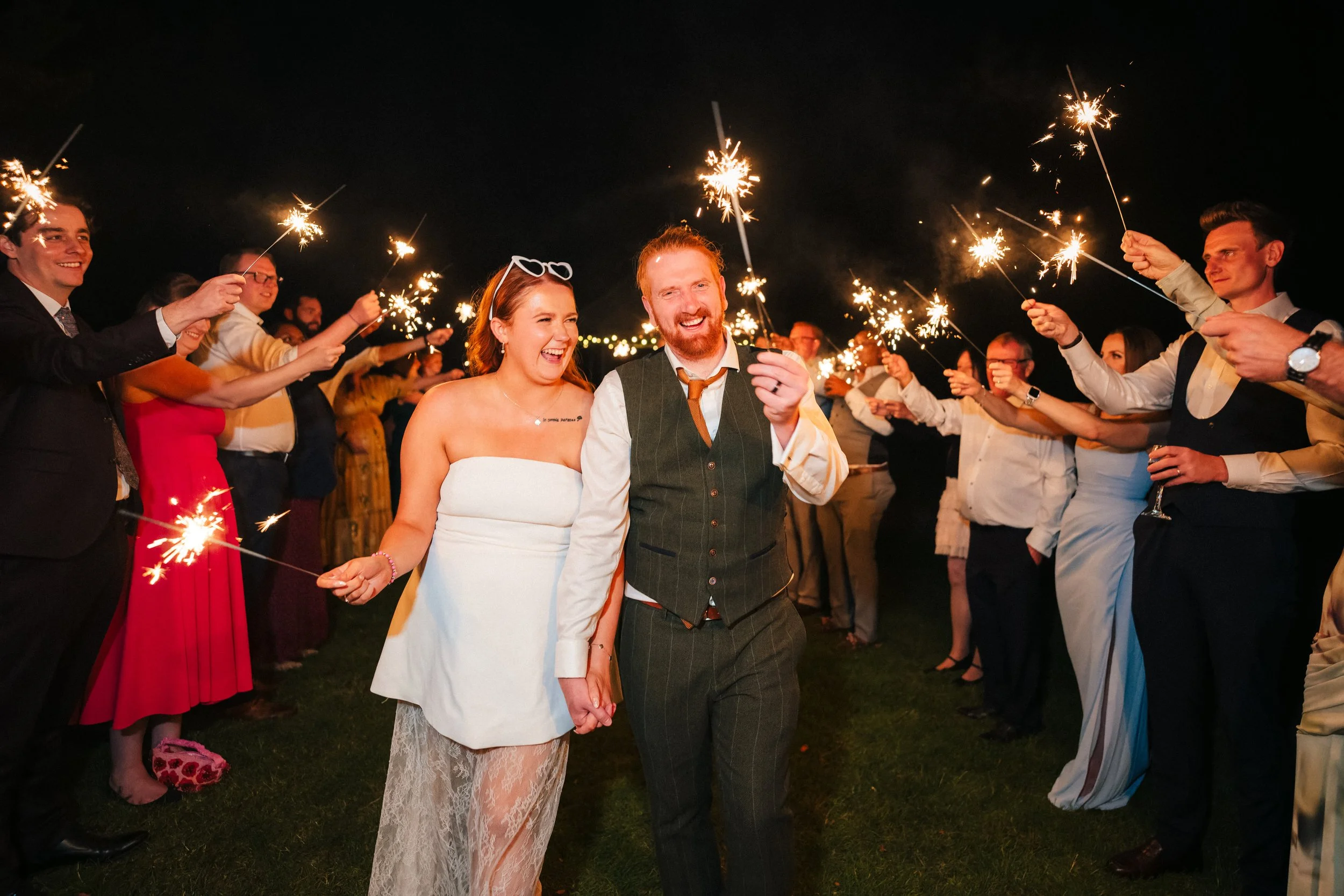 BREDENBURY COURT BARNS WEDDING PHOTOGRAPHER - bride and groom walking on the lawns at Bredenbury Court Barns holding Sparklers