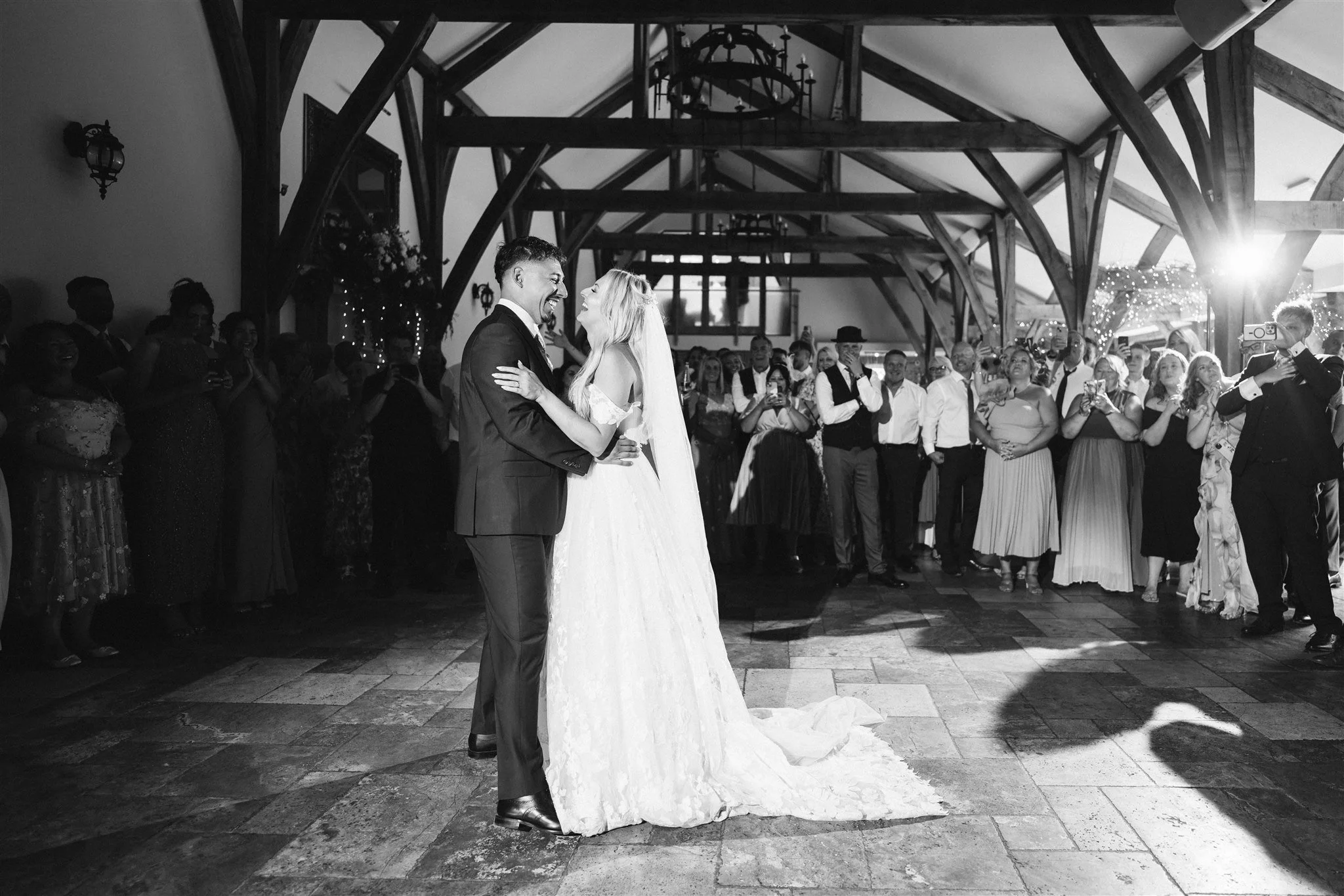 Bride and groom sharing their first dance surrounded by guests at their Swancar Farm wedding reception, inside the beautifully timber-framed barn – relaxed, documentary-style wedding photography by SaywellHQ.co.uk