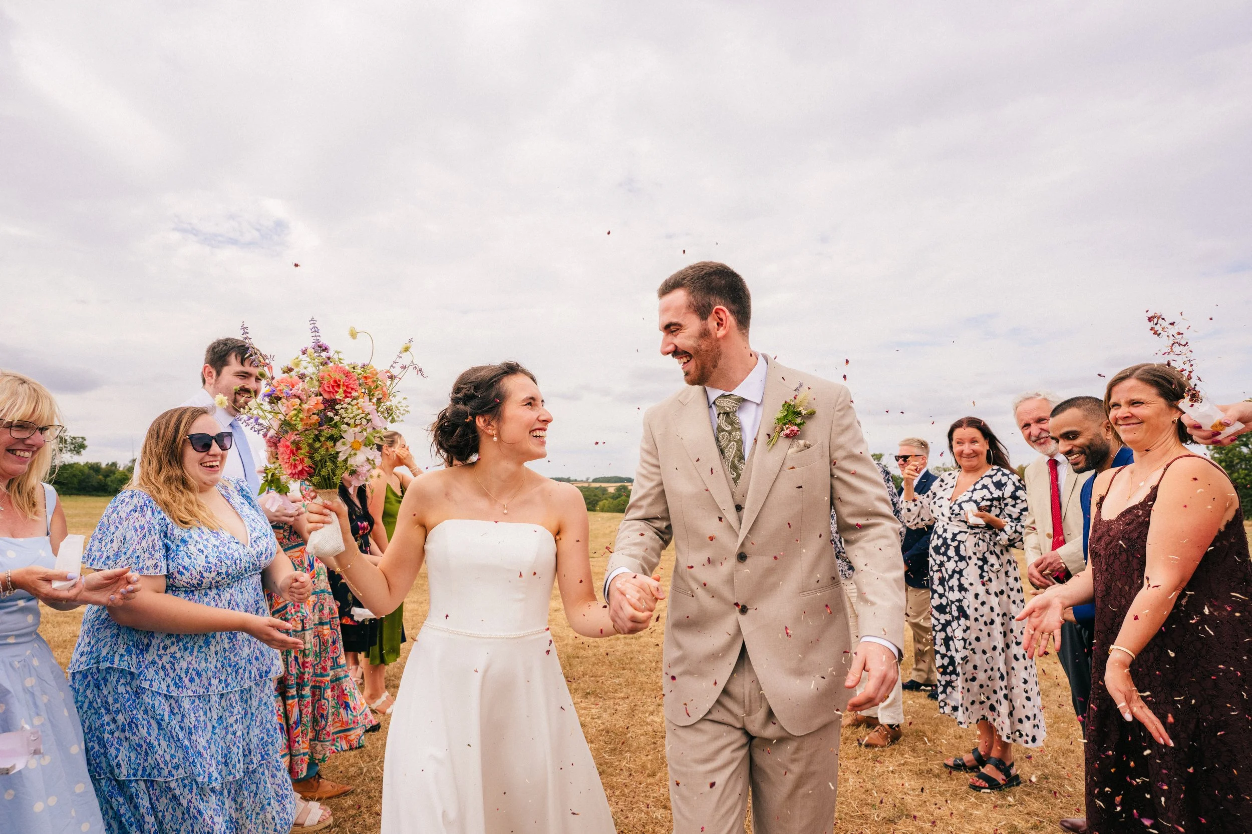 Bride and Groom getting covered on confetti at THE TRACTOR BARN in Northampton