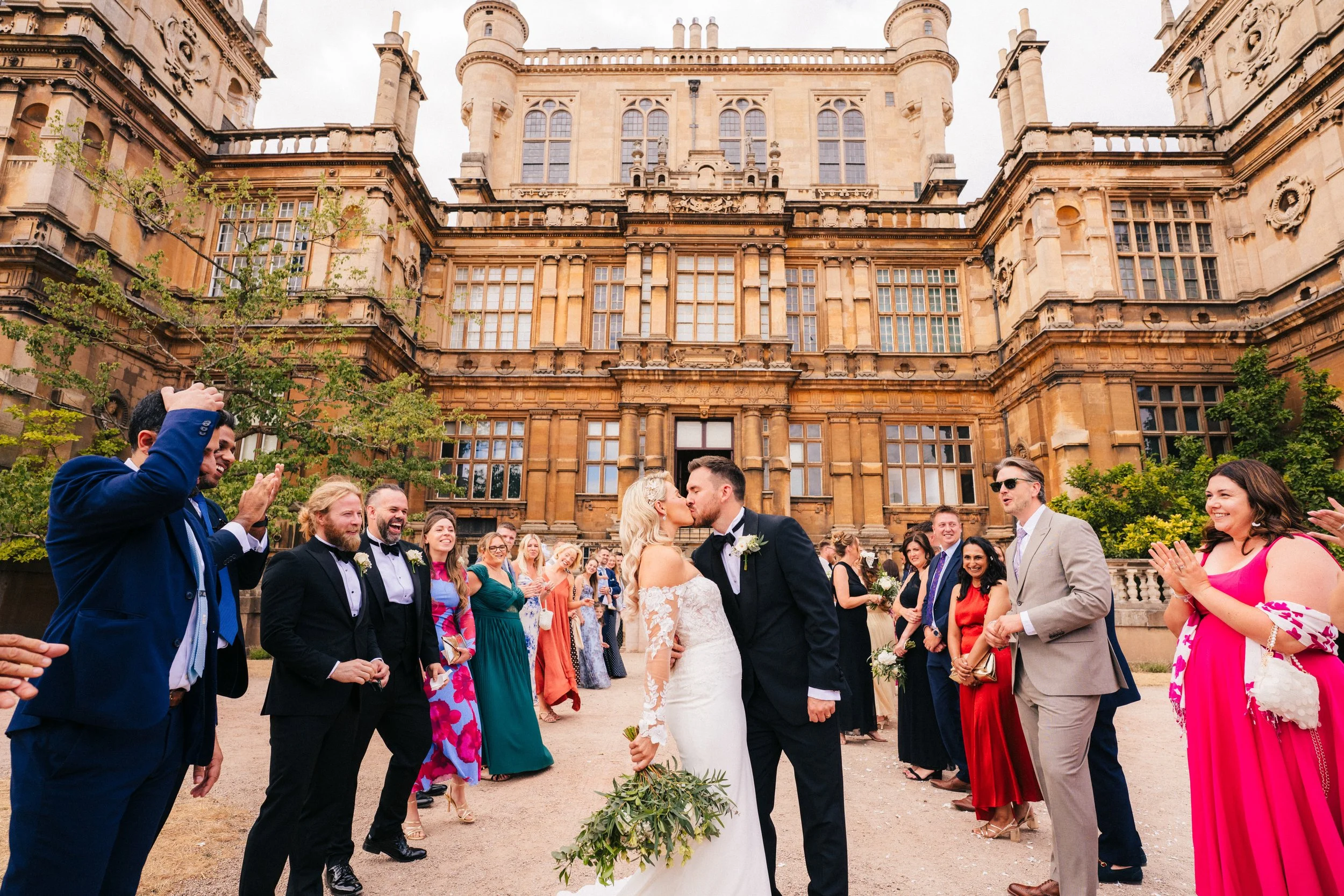 Bride and groom kissing in front of the Main Hall following the confetti at a Wollaton Hall Wedding