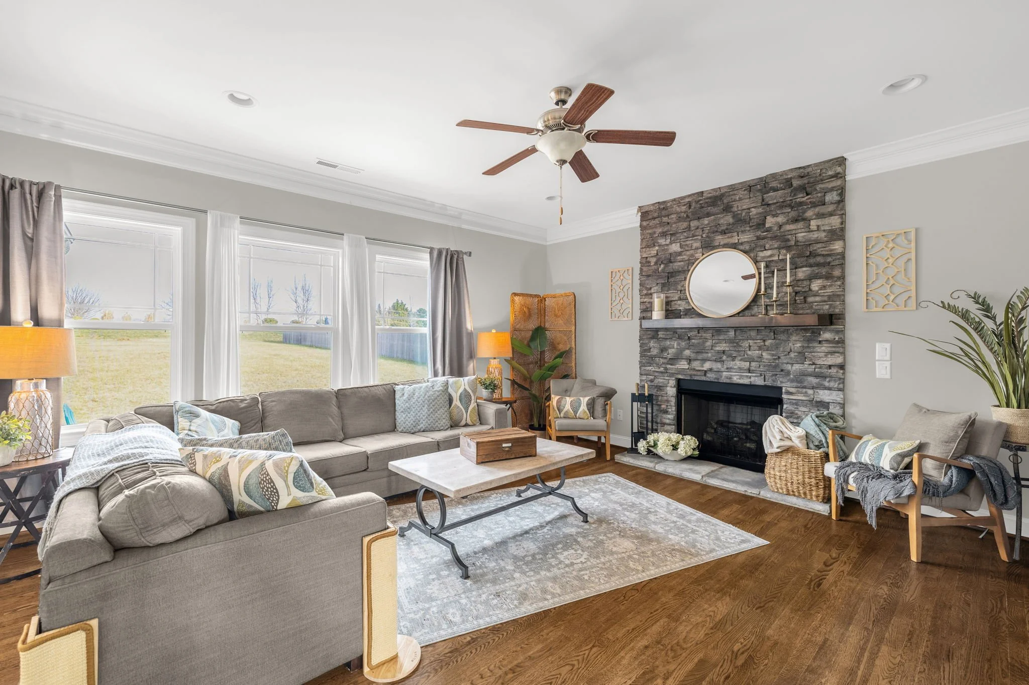 Living room with stacked stone fireplace and hardwood floors at 8012 NW Meadows Drive, Stokesdale, NC 27357. Listed by Delia Knight, REALTOR® with Howard Hanna Allen Tate Real Estate.