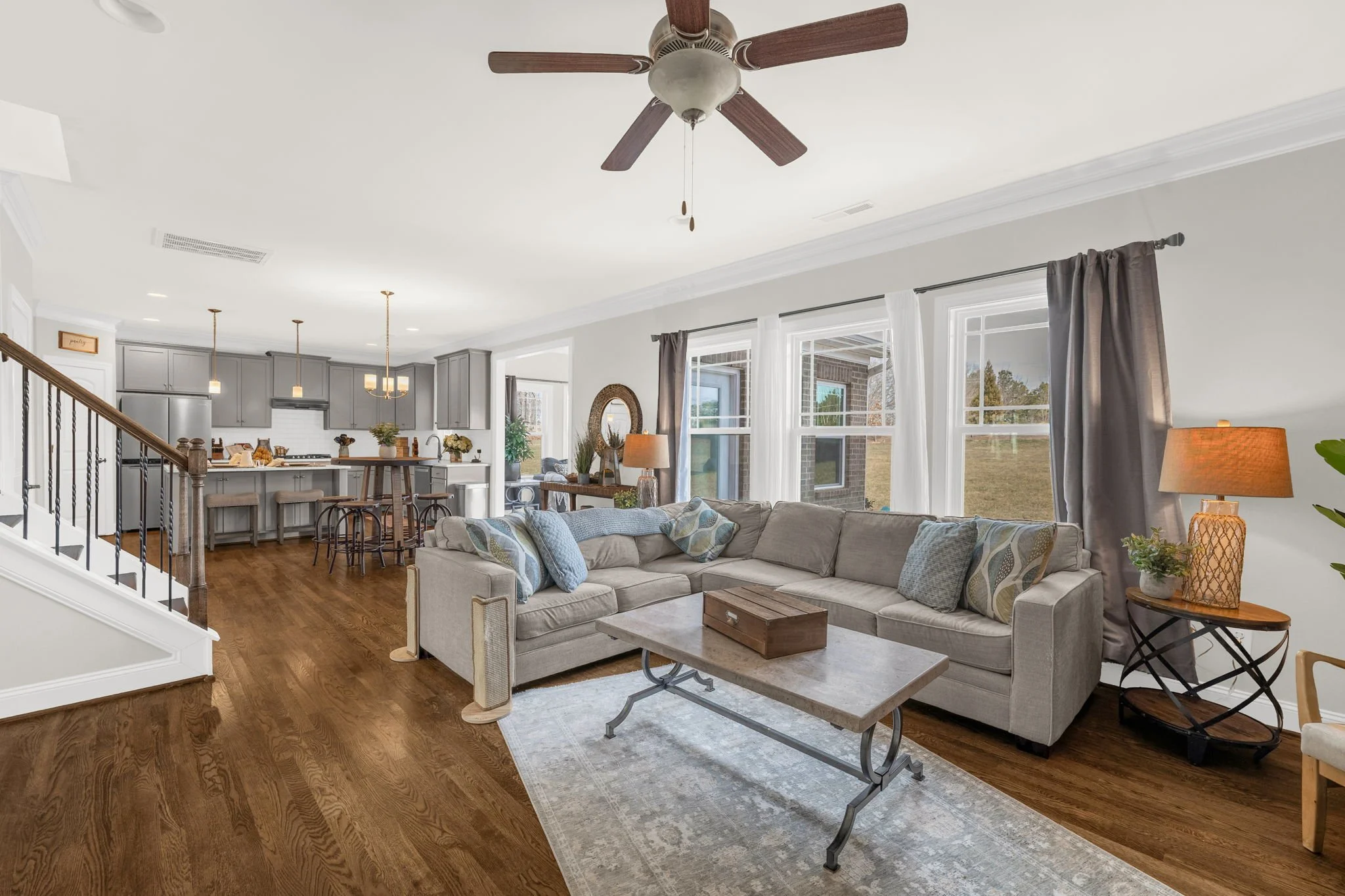 Open-concept living room to kitchen with iron staircase at 8012 NW Meadows Drive, Stokesdale, NC 27357. Listed by Delia Knight, REALTOR® with Howard Hanna Allen Tate Real Estate.