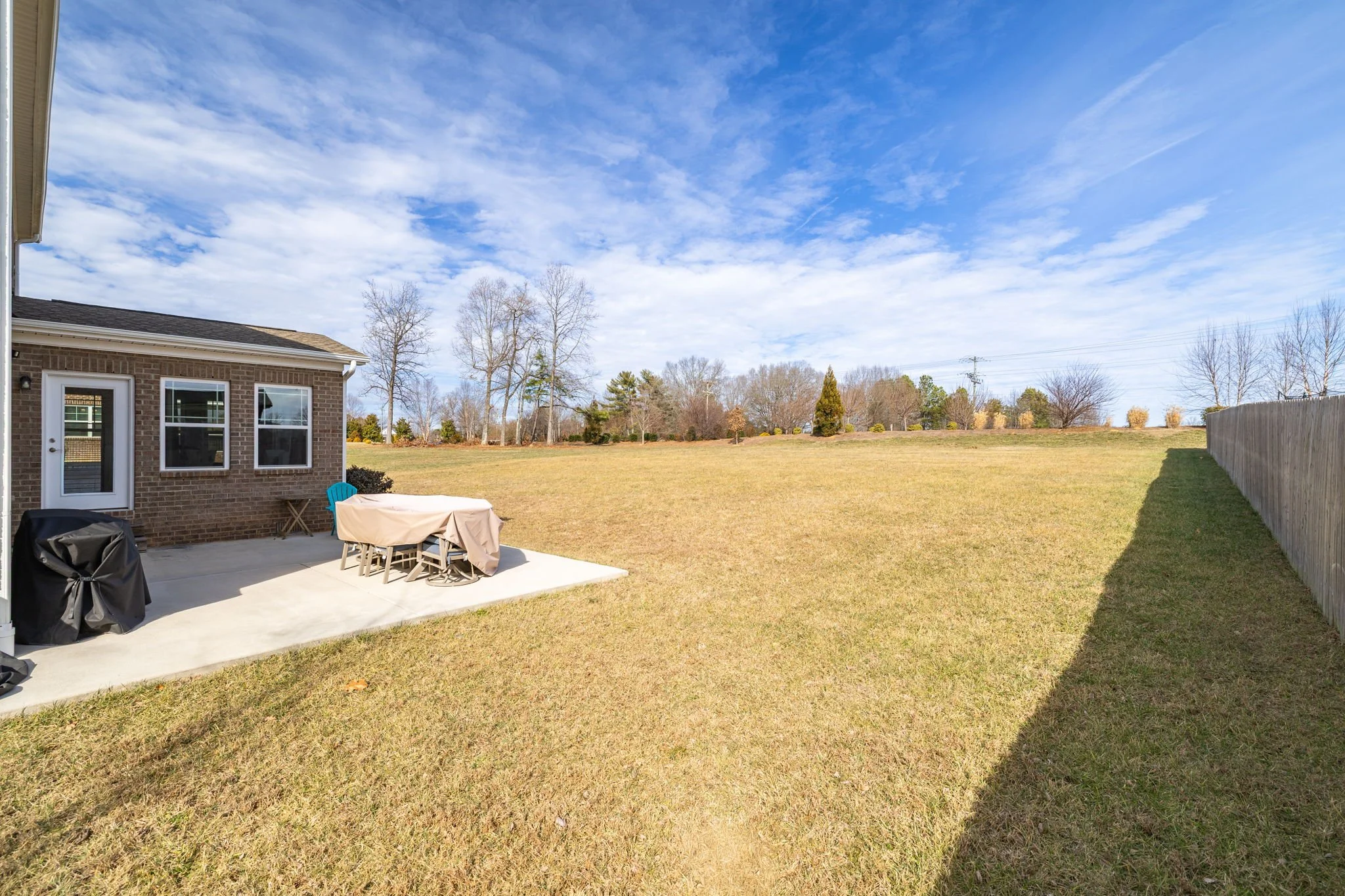 Large fenced backyard with patio at 8012 NW Meadows Drive, Stokesdale, NC 27357. Listed by Delia Knight, REALTOR® with Howard Hanna Allen Tate Real Estate.