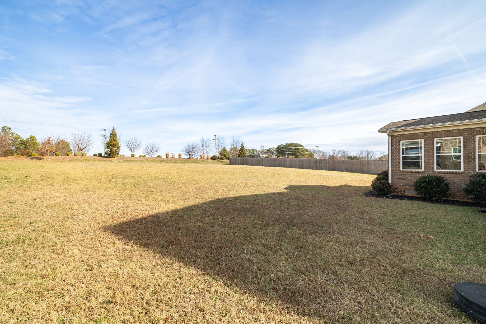 Side yard and fenced backyard at 8012 NW Meadows Drive, Stokesdale, NC 27357. Listed by Delia Knight, REALTOR® with Howard Hanna Allen Tate Real Estate.
