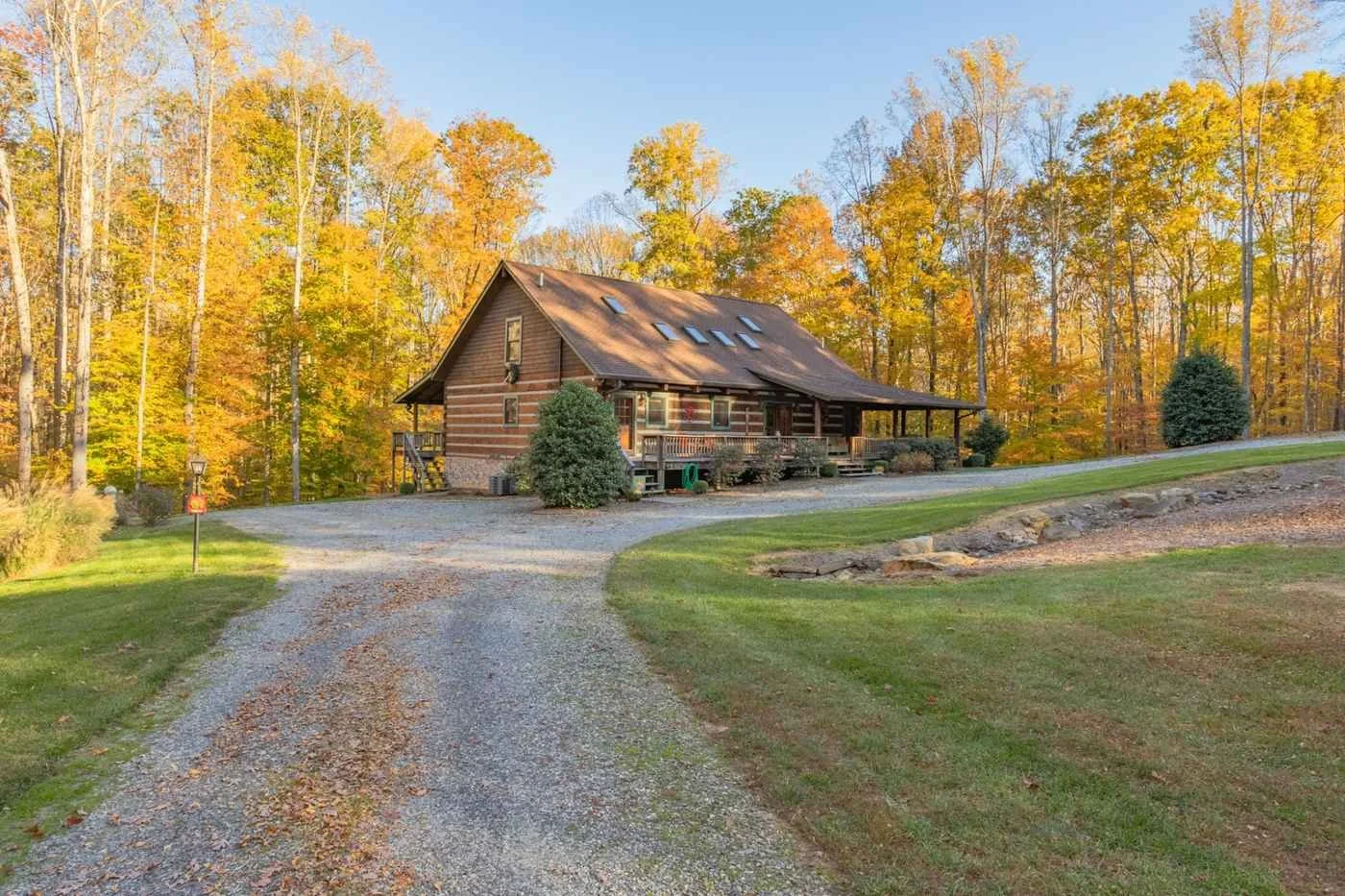 Log home with gravel driveway surrounded by fall foliage in a rural North Carolina setting