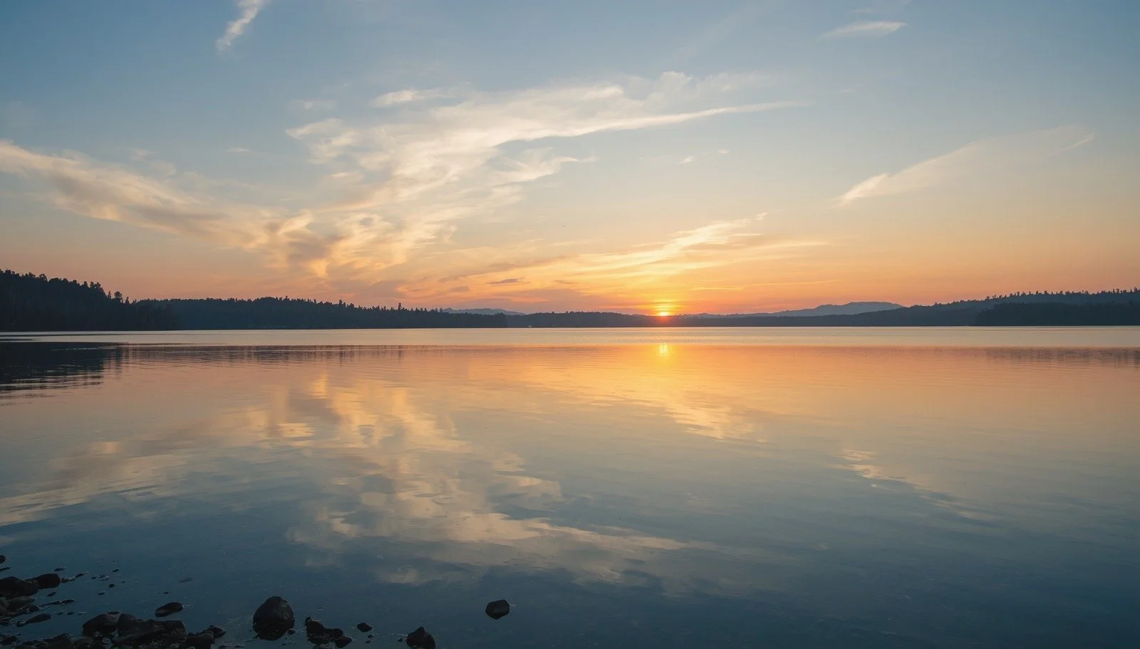 Sunset over a calm lake with forest silhouette and reflected clouds in the Piedmont Triad, NC