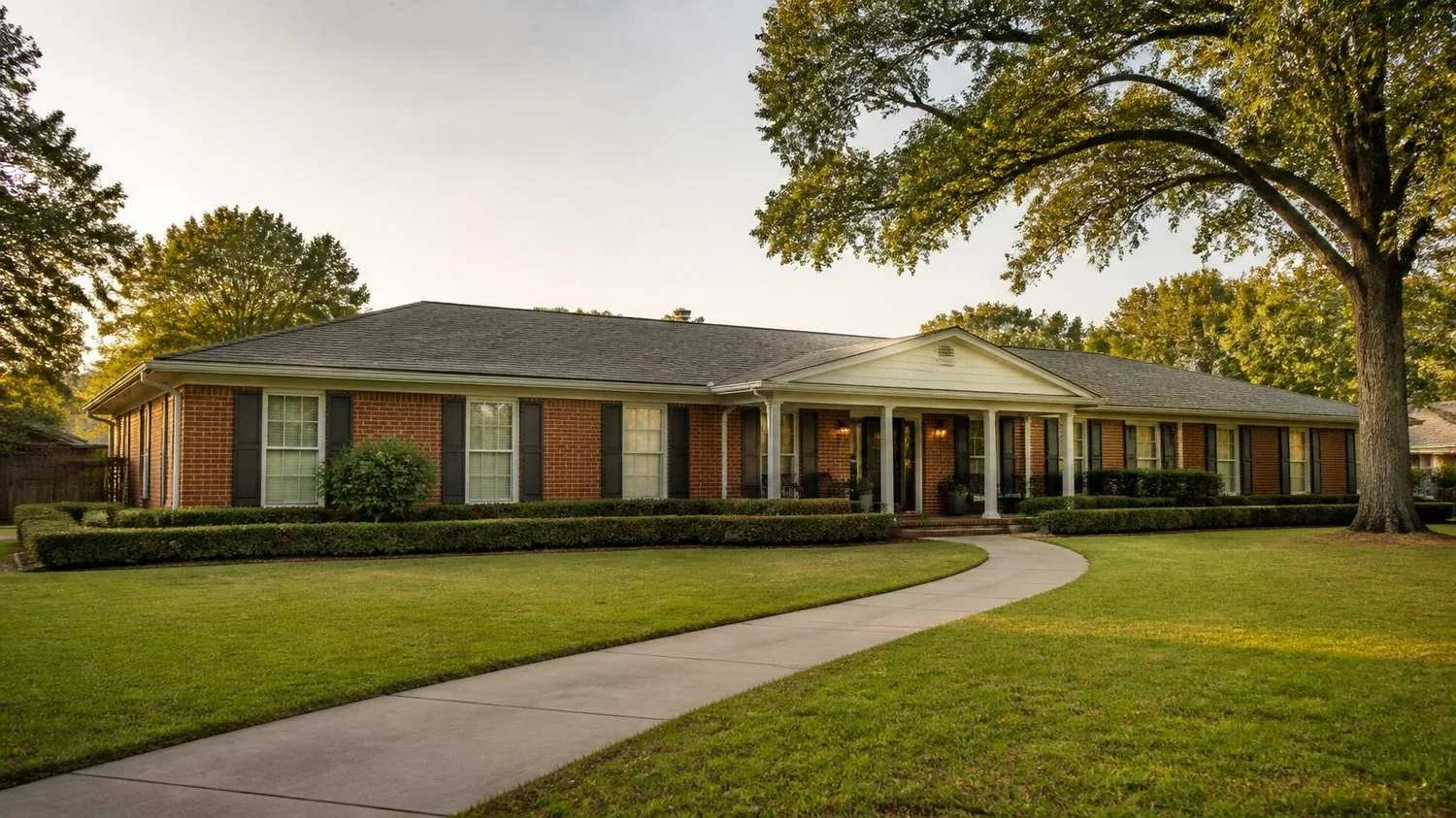 Red brick ranch home with mature trees and a covered front porch in an established Greensboro, NC neighborhood