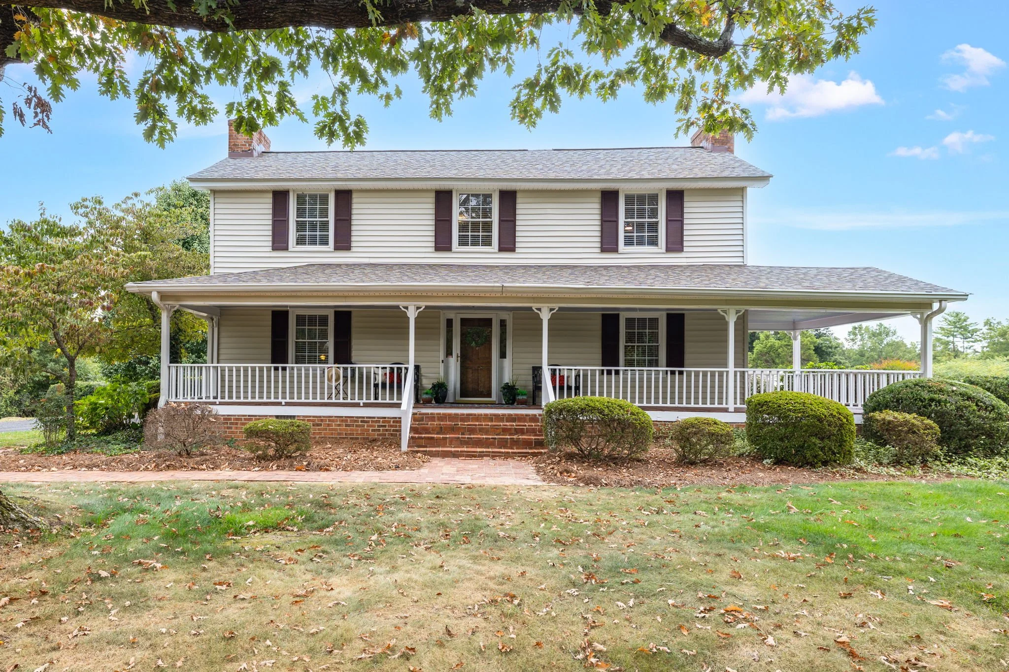 Front exterior view of 2190 Lindsey Bridge Rd in Madison, NC – charming white farmhouse with wraparound porch, listed by Delia Knight, REALTOR®
