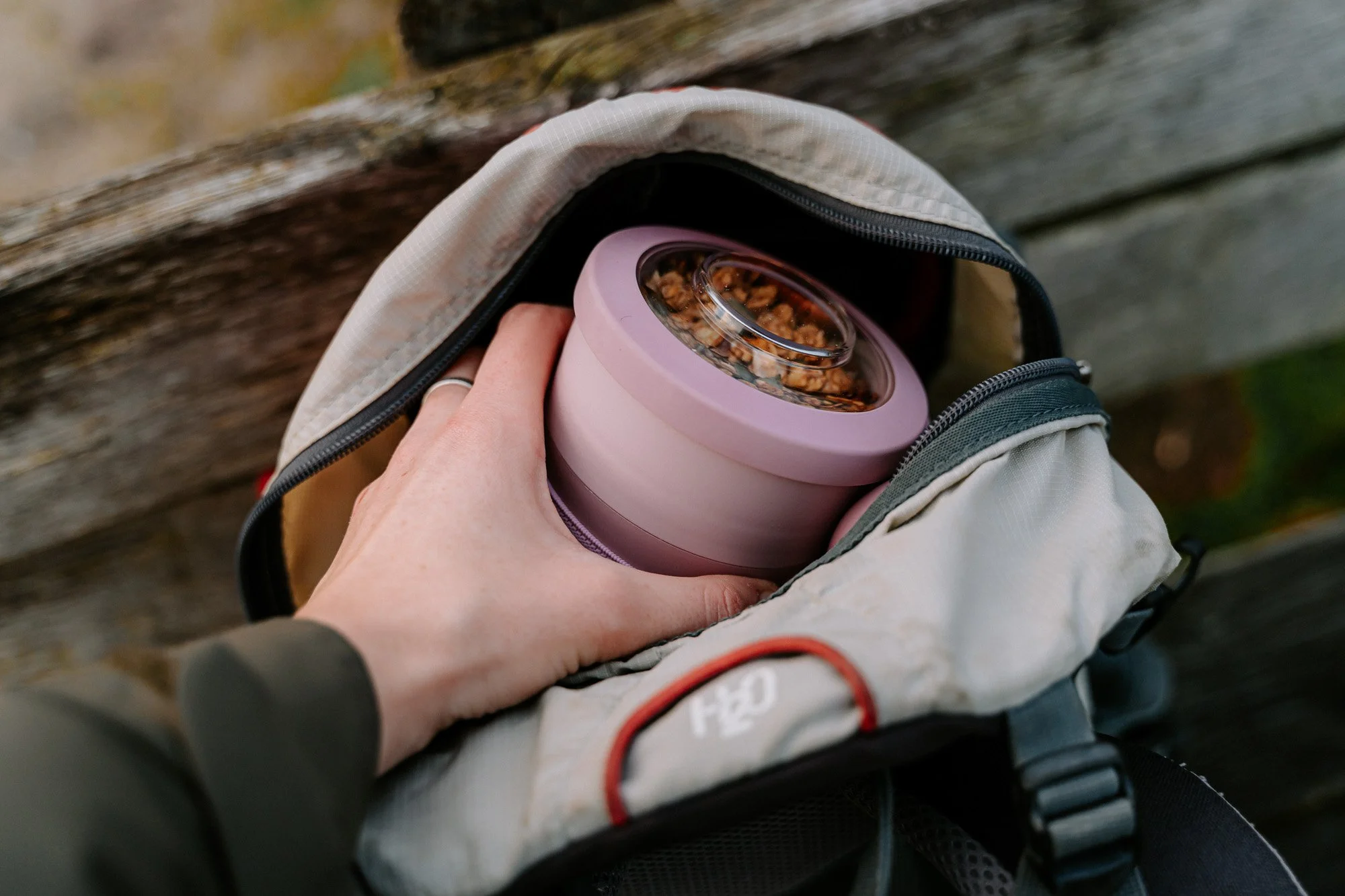 Persoon plaatst een doosje met granola in een rugzak.