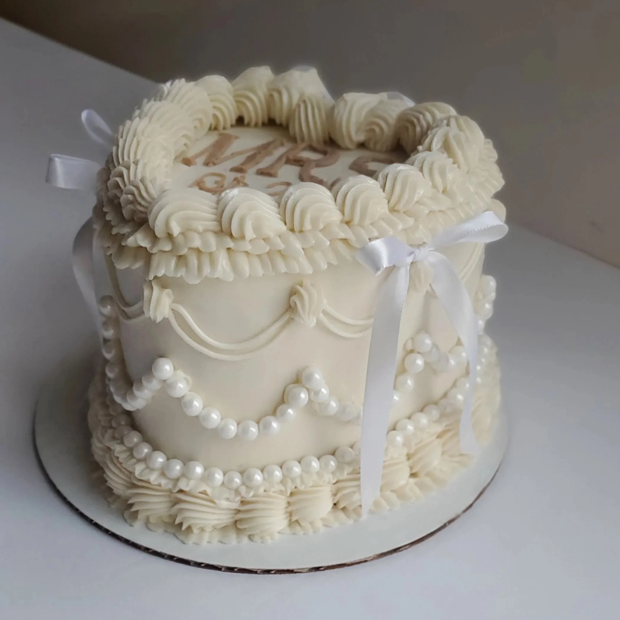 white vintage heart engagement cake with pearl draping and bows