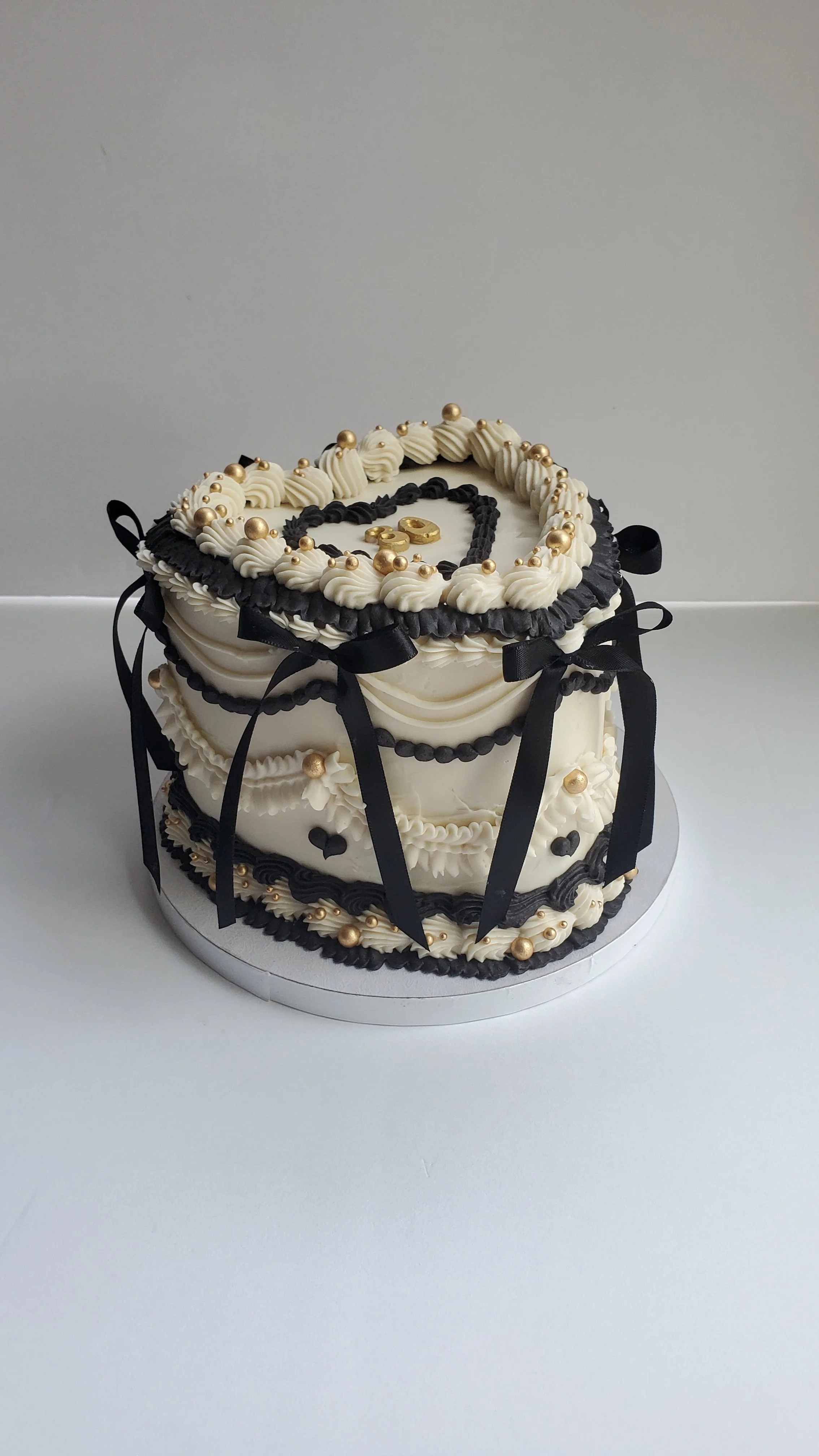 white and black vintage heart cake with gold pearls and bows