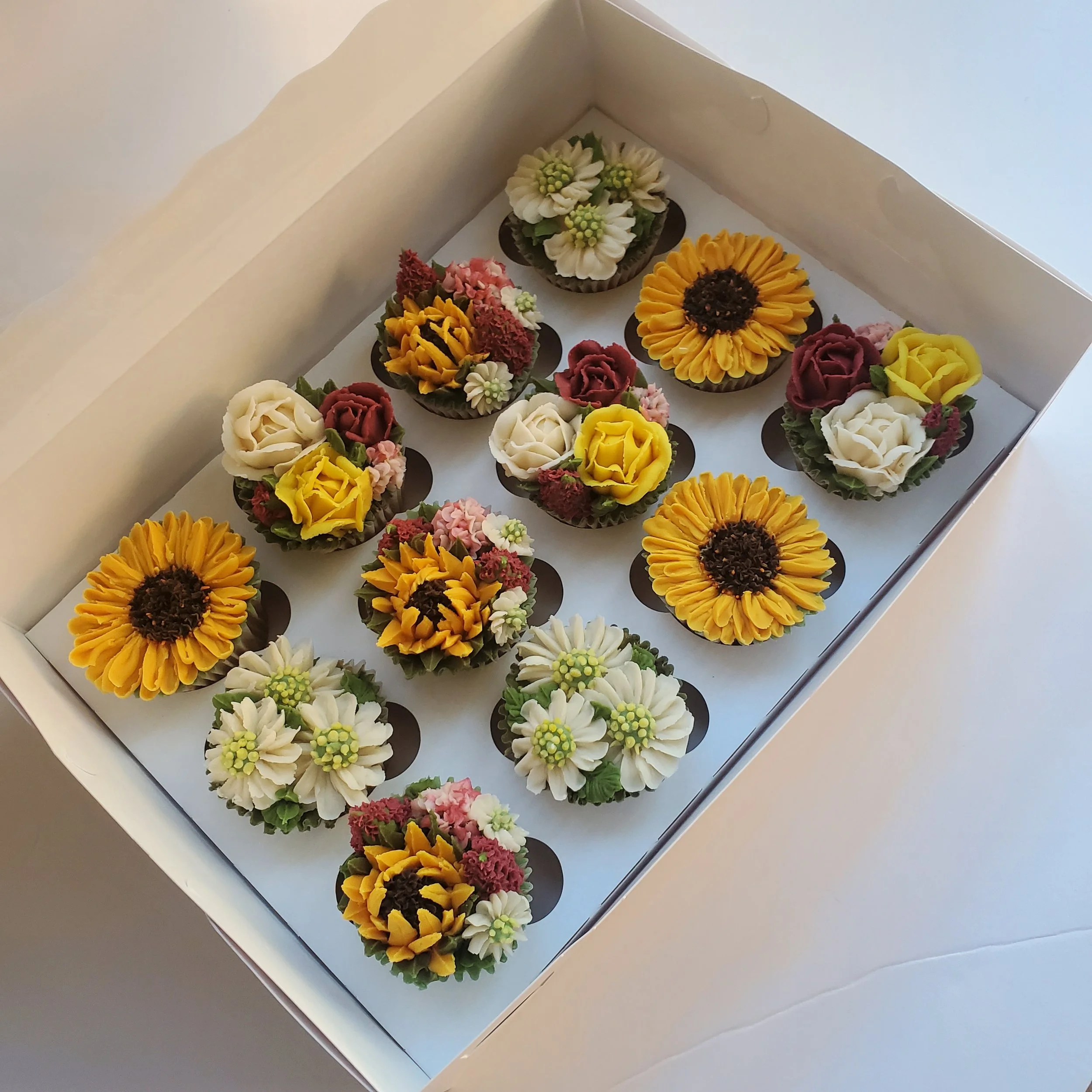 buttercream floral cupcakes with sunflowers, daisies, and roses