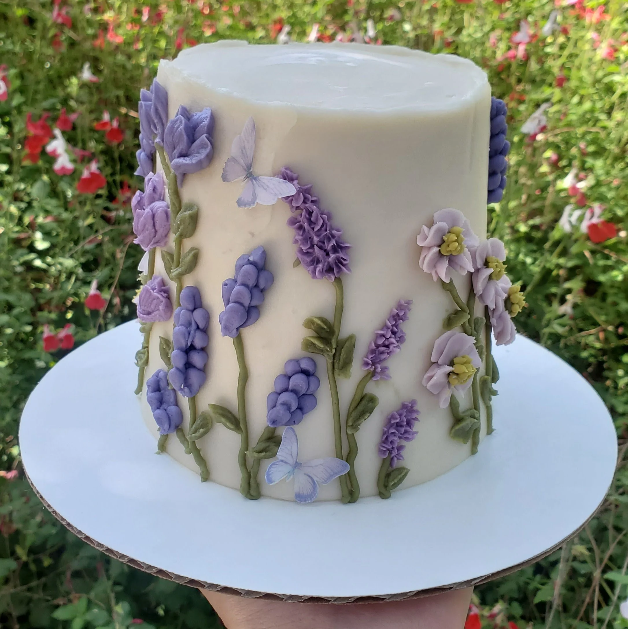 cake with purple buttercream wildflowers and edible butterflies