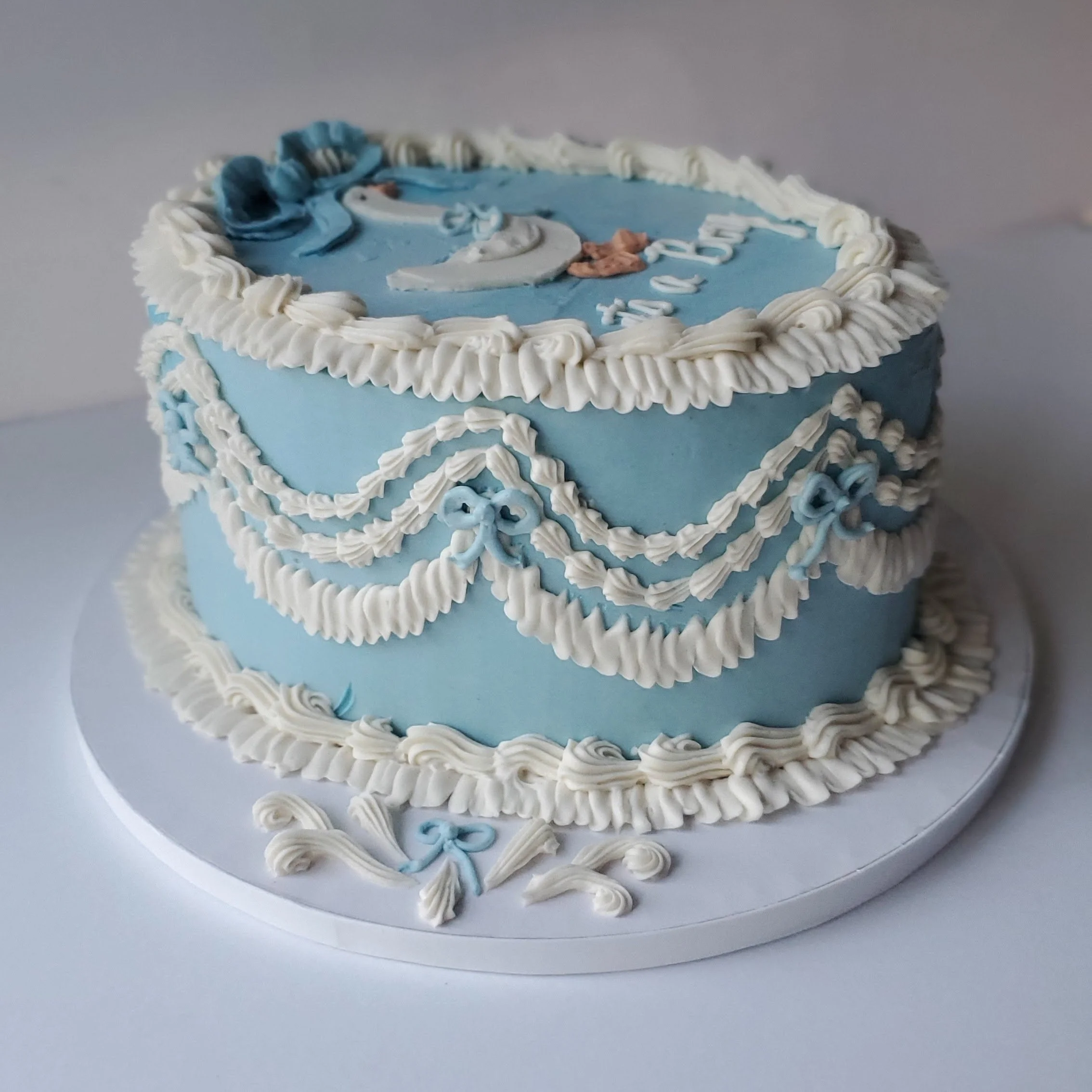 blue and white oval vintage baby shower cake with goose