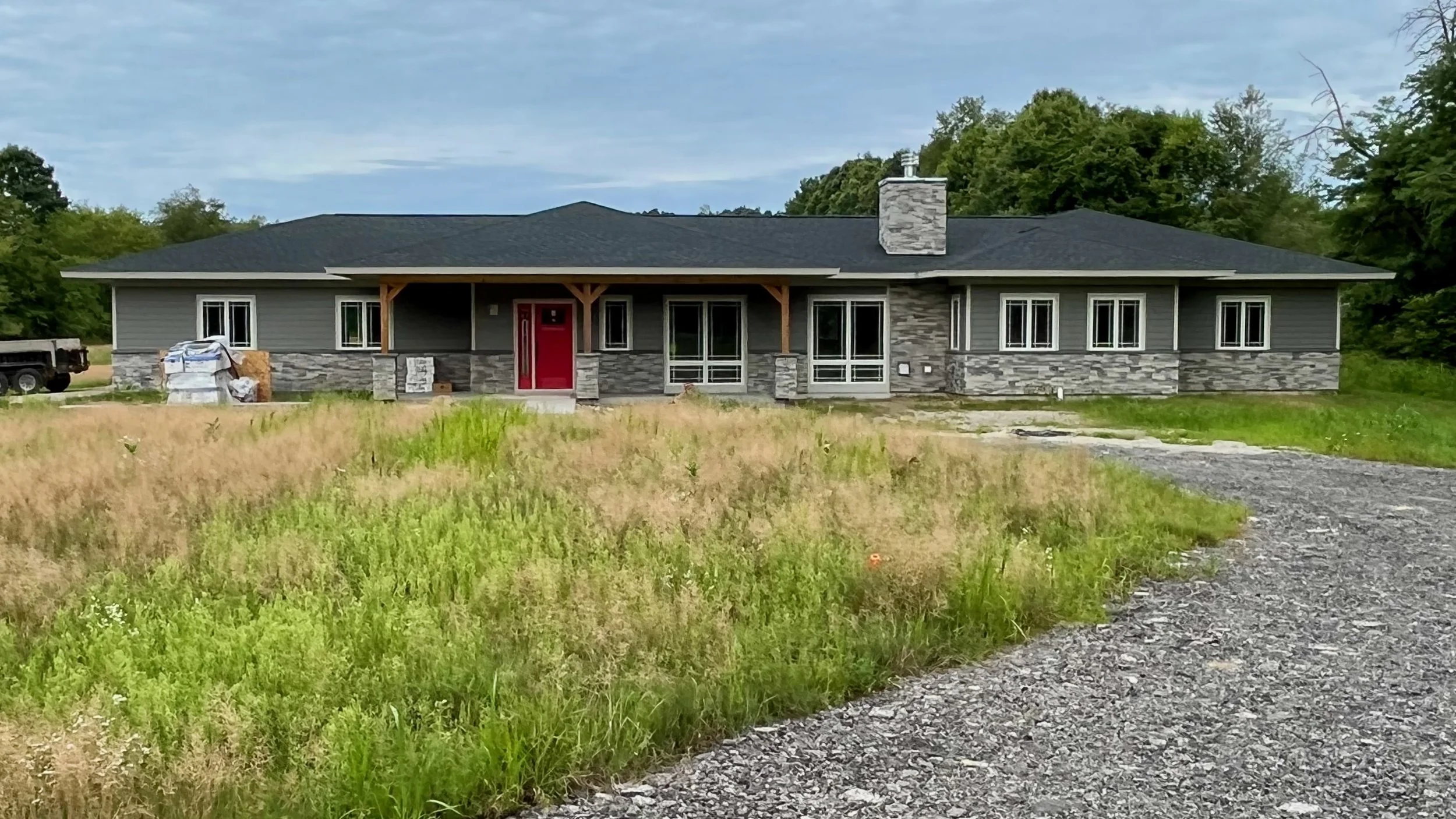 Wide view of finished new home construction with a red entry door.