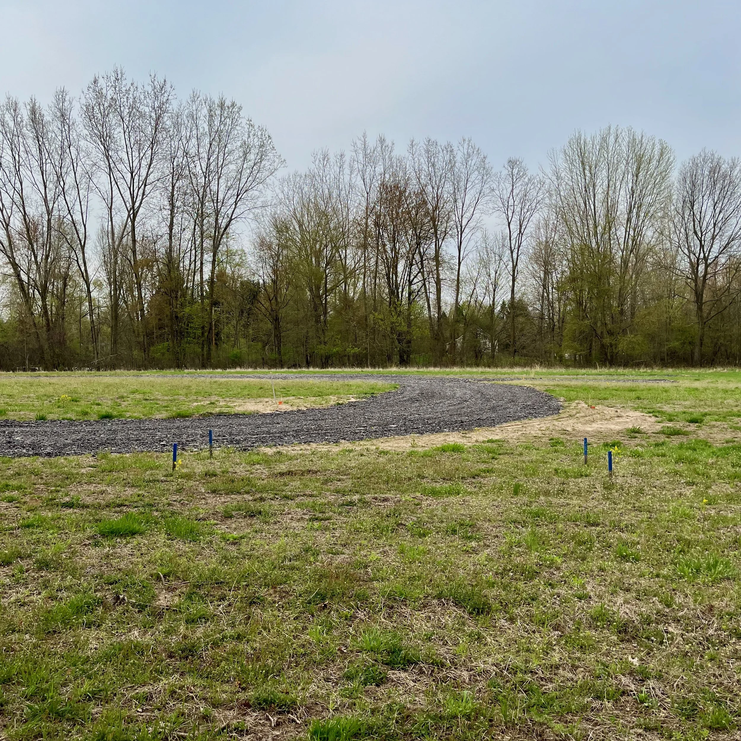 Vacant land where a new home will be constructed from the ground up. A driveway has been installed.
