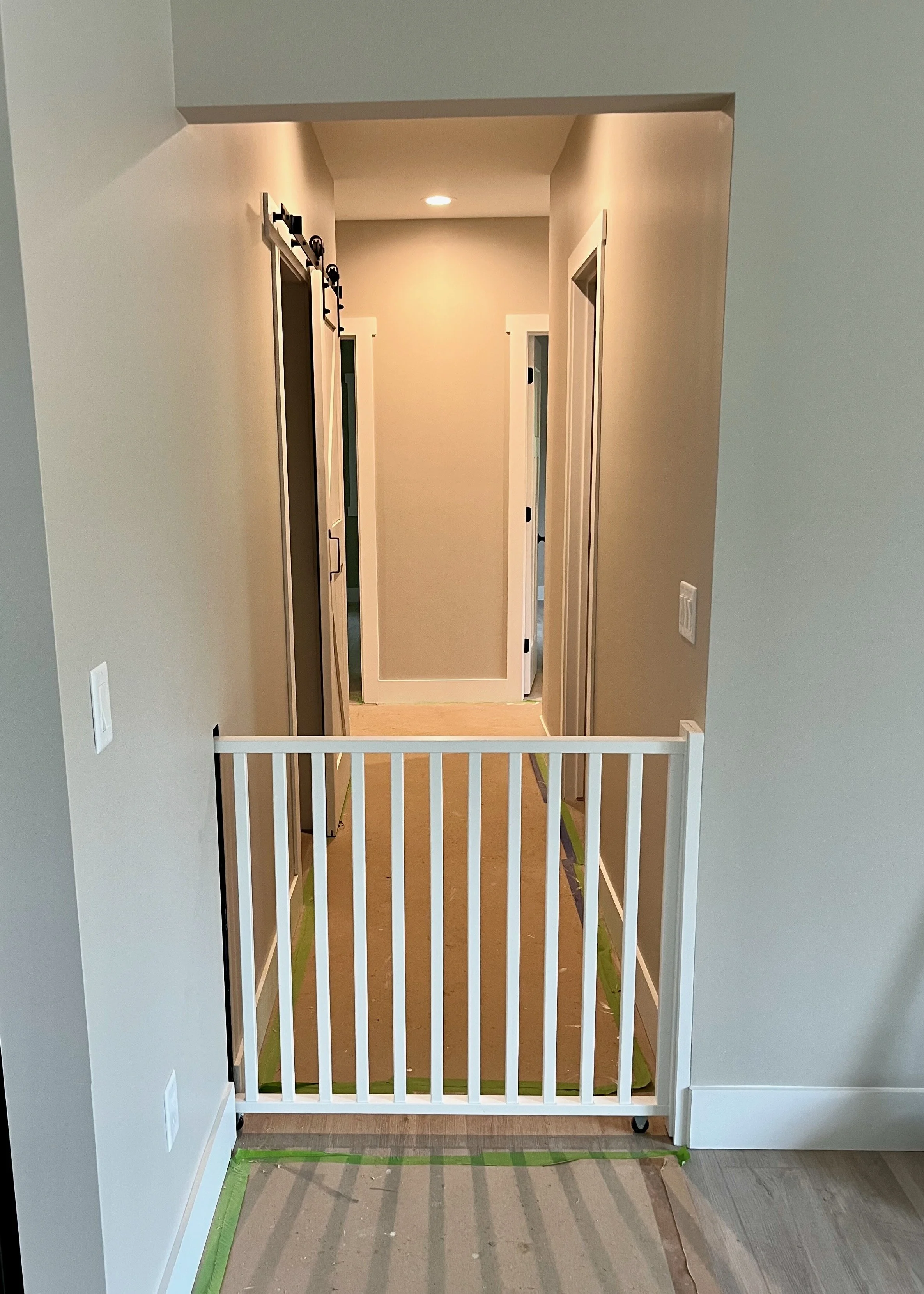Sliding dog gate extending from wall to stop dogs from walking through hallway.