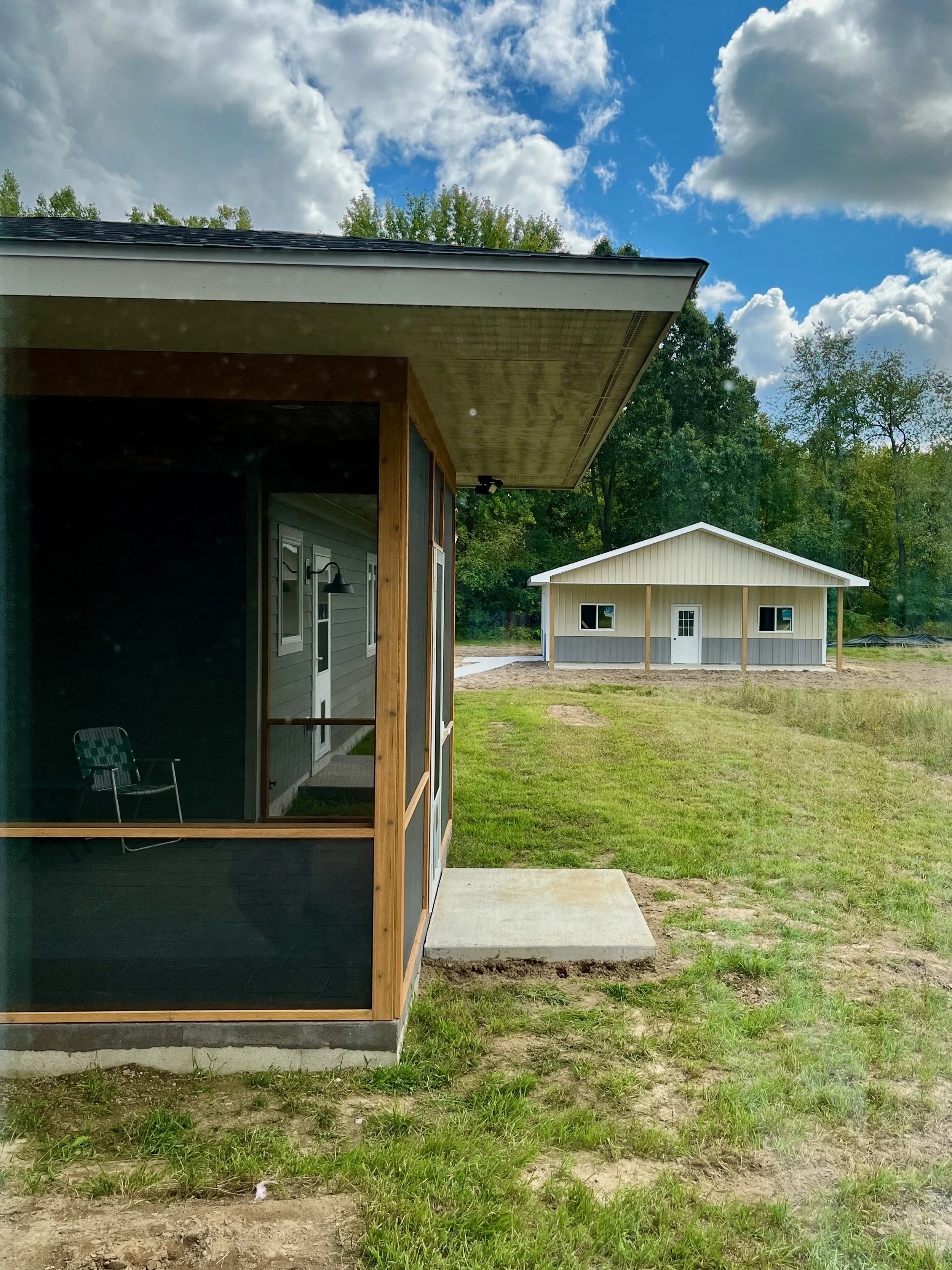 Screened in porch with large overhanging eaves. A new construction garage sits in the background.