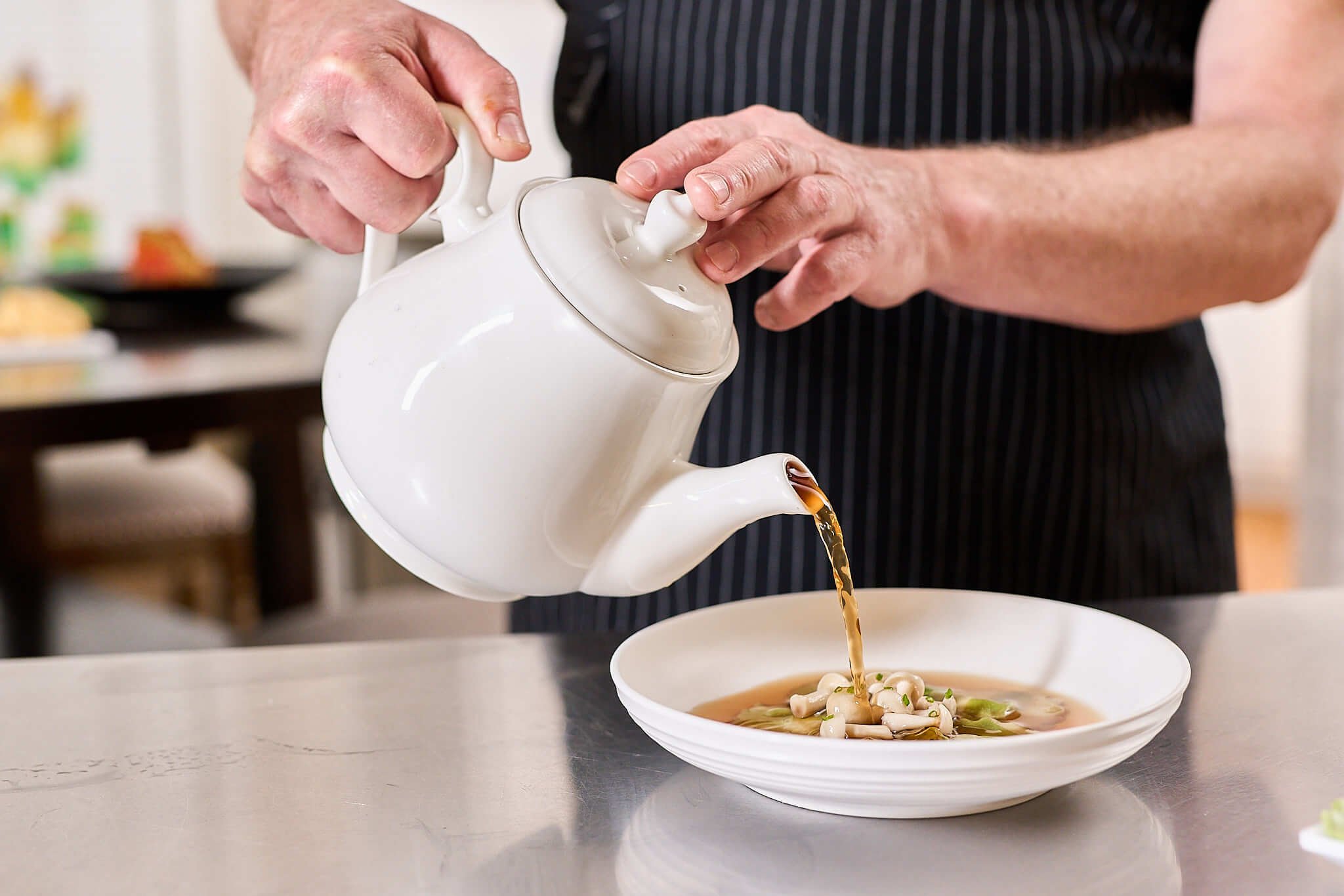 Personal Chef, David de Quay pouring a delicate broth over raviolis to serve table side at an elegant dinner party in Chicago