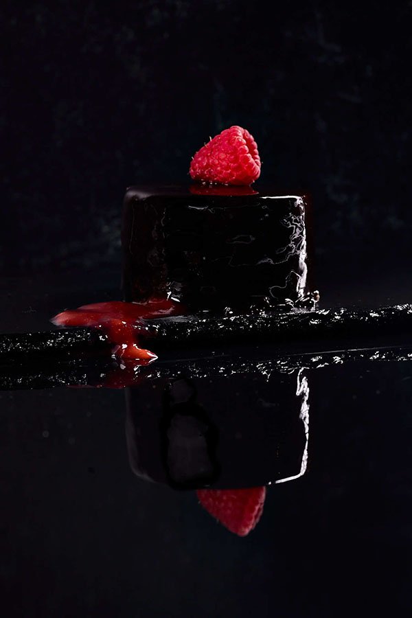 lava cake style dessert on black background topped with raspberry filling