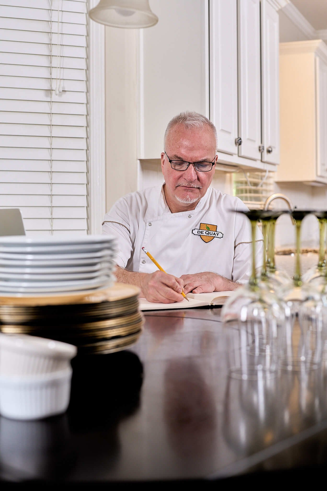 Private Chef David de Quay sitting at a table writing menus surrounded by elegant tableware