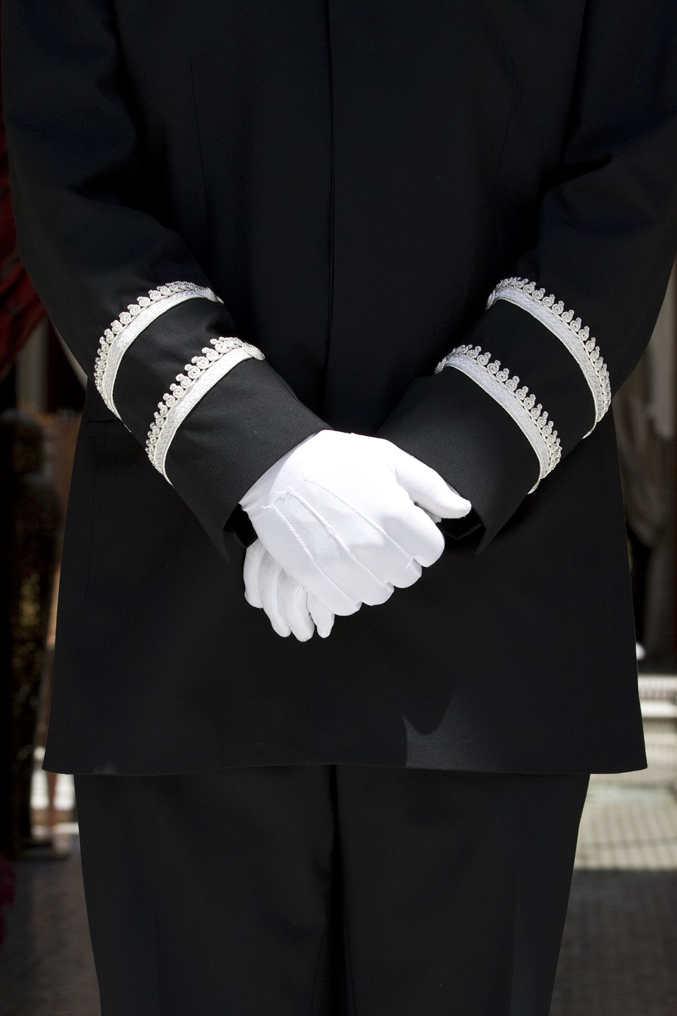 Butler di industri perhotelan mengenakan seragam hitam dan sarung tangan putih