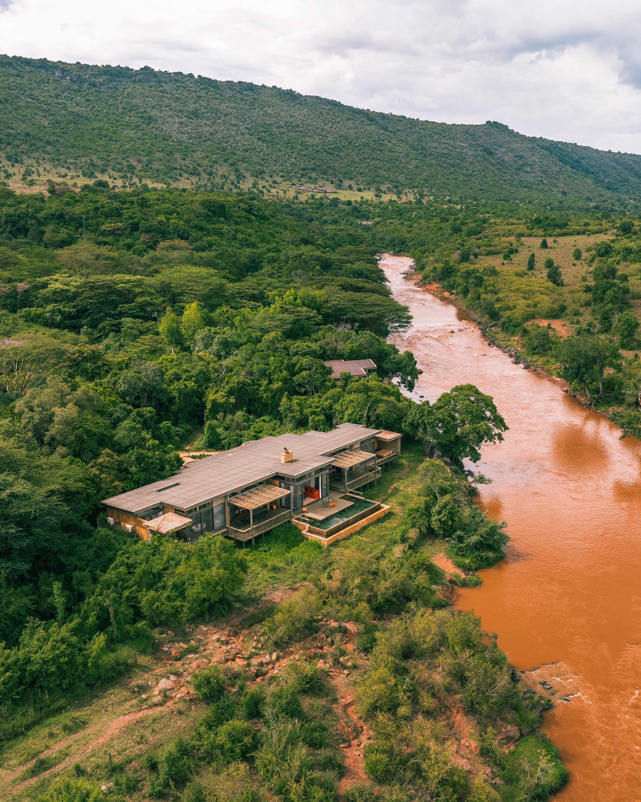 Shooting architecture like this is a race against the light. The Geoffrey Kent Suite at Olonana faces the Mara River through one long wall of glass, so you work the interiors while the sun is behind the escarpment, then get the drone up before the cl