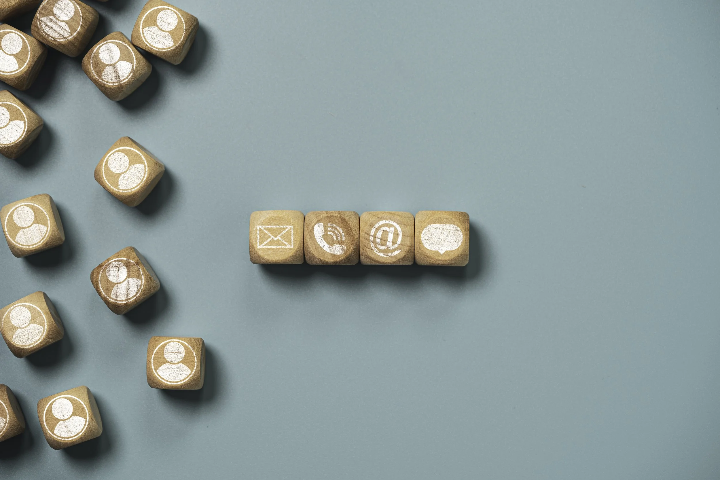 Holzwürfel mit Kontakt- und Kommunikationssymbolen auf blauem Hintergrund