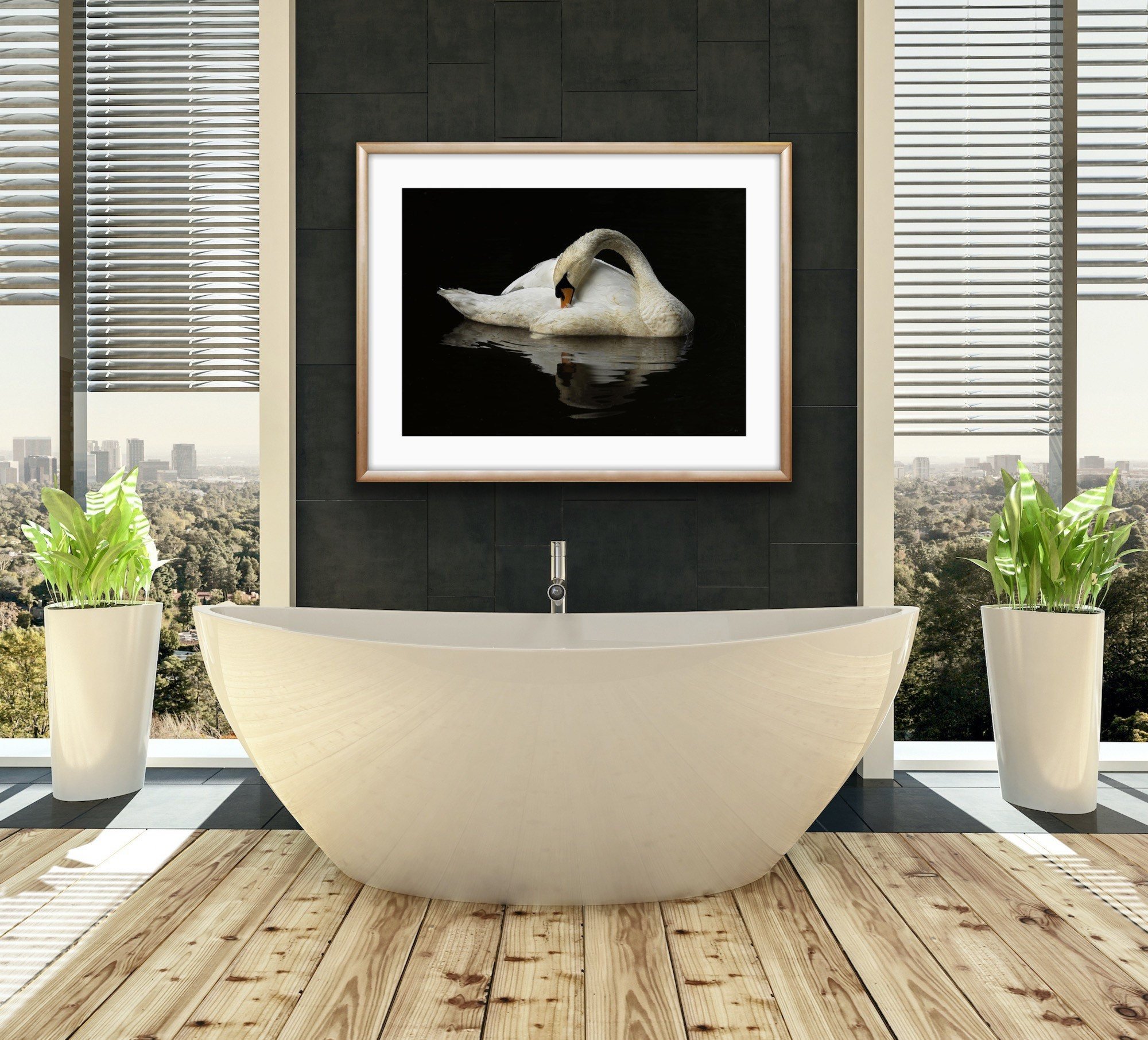 Modern bathroom with freestanding bathtub, black tiled wall, framed swan photograph, and large windows with city view. Potted plants on either side of the bathtub.