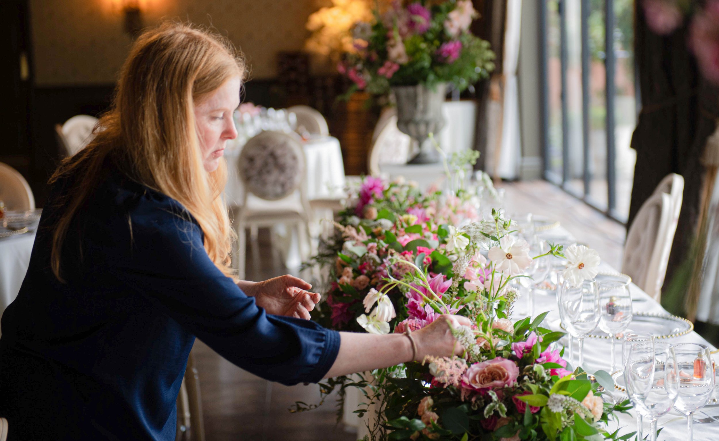 Florist adding finishing touches to wedding top table arrangement 
