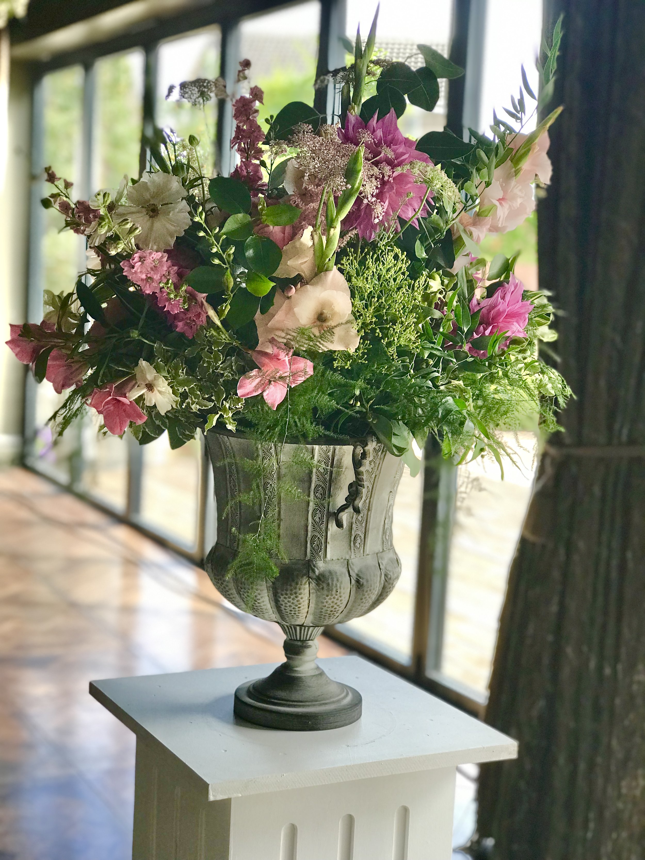 Large urn arrangement on pedestal, pinks and coral flowers