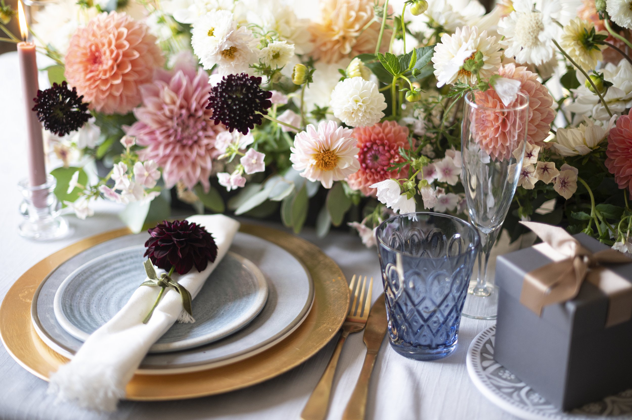 Place setting in blues and gold with tablescaped flowers 