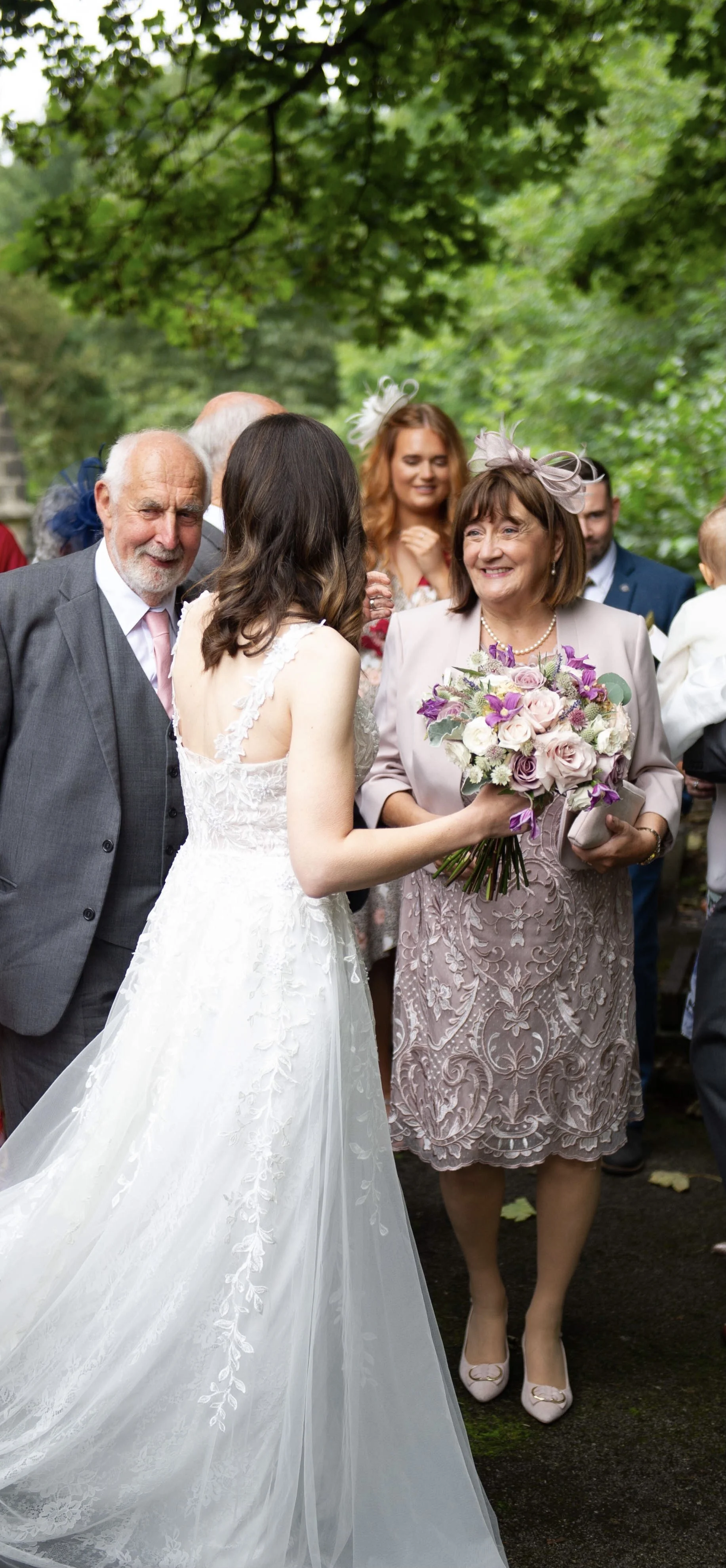 Bride holding bouquet greeting her parents