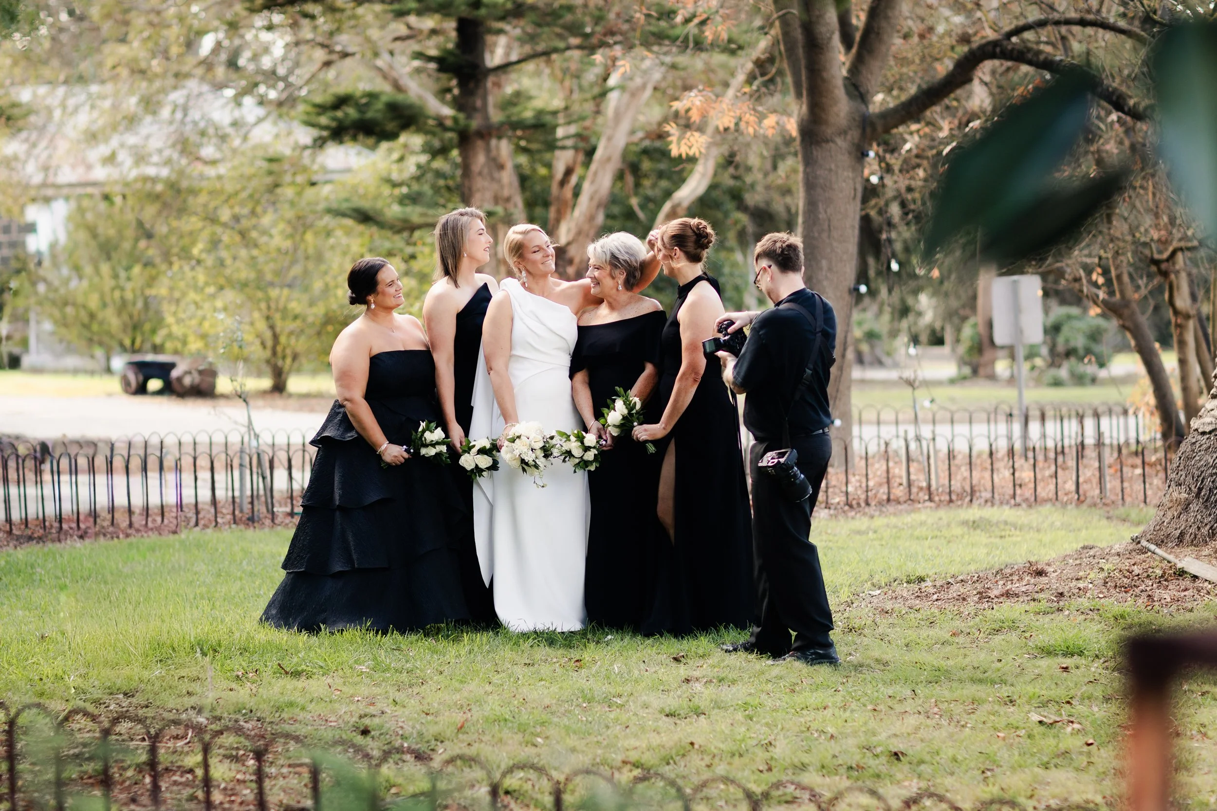 A bridal party, dressed elegantly, gathering outdoors at Provenance Wines Geelong, for wedding photos, with a wedding photographer Tal Lemmens taking pictures.
