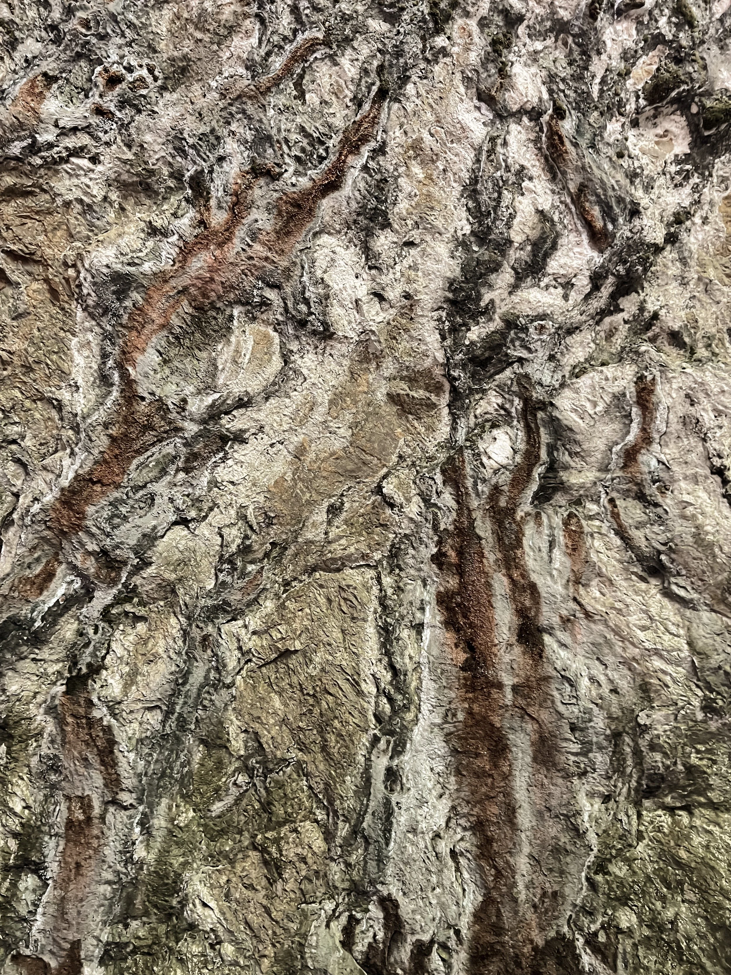 Close-up of layered mineral rock texture with earth tones, used as a sensory reference for matter, time and tactile perception in neuro-spatial design.