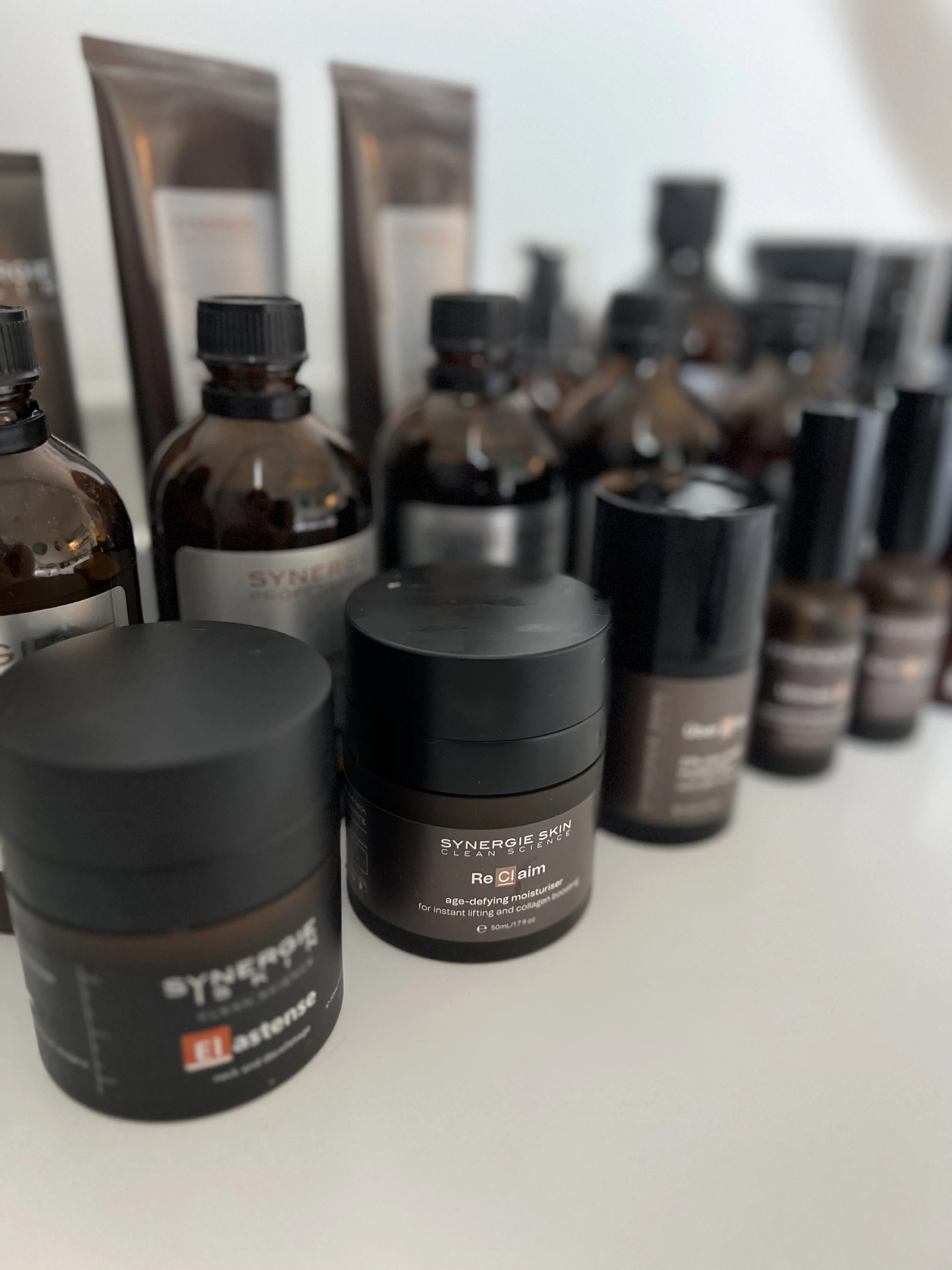 Assorted skincare products, including bottles and jars, arranged on a white surface.