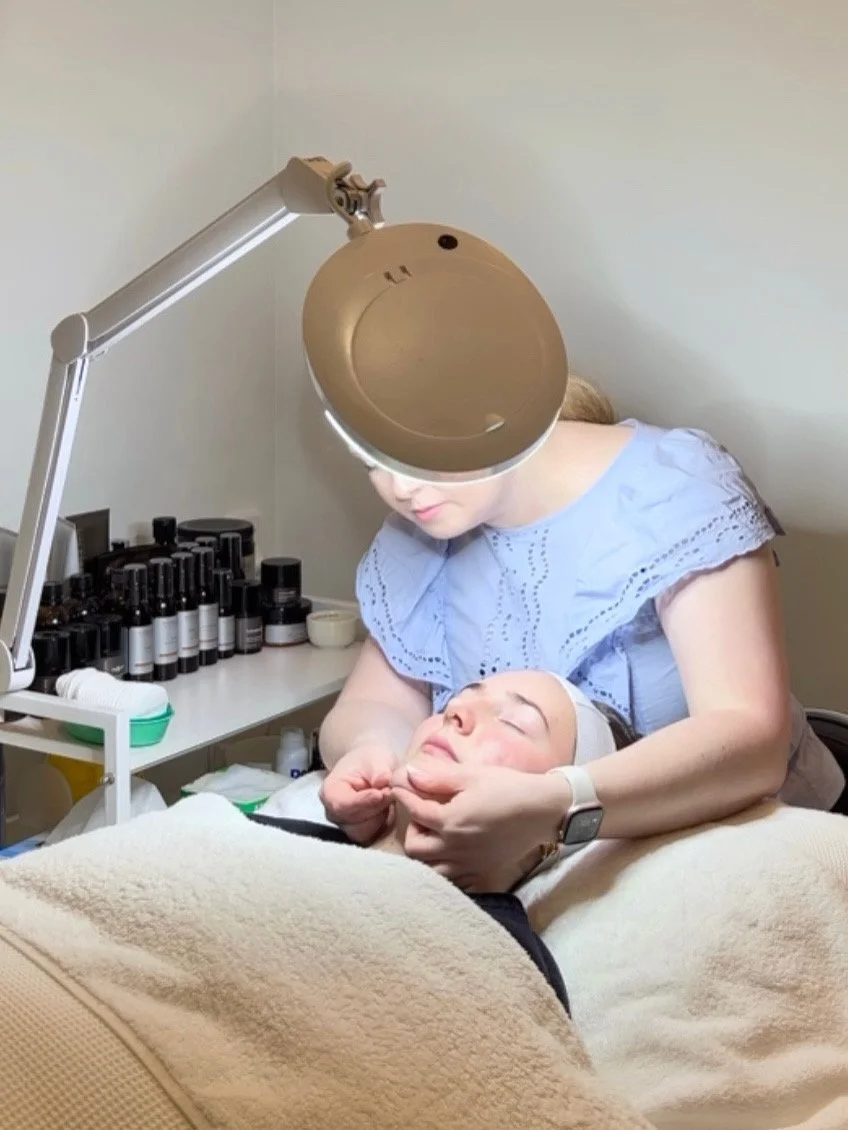 Michelle, medical skin therapist and founder of MiSkin, analysing a client’s skin with professional skincare products beside the treatment bed.
