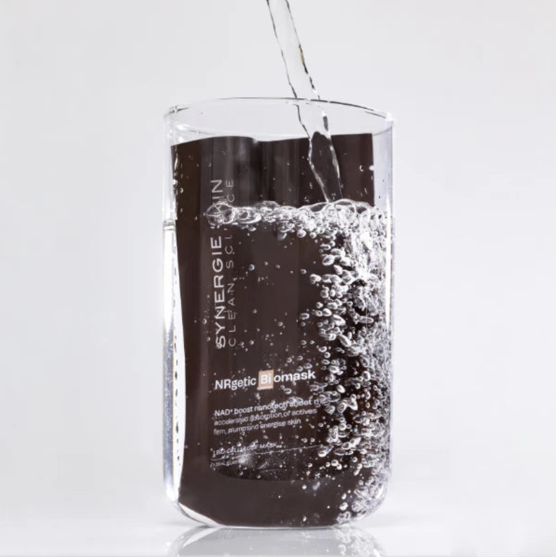 A clear glass being filled with a dark liquid, creating bubbles and foam inside the glass.