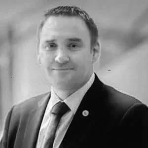 Black and white photo of a man in a suit smiling at the camera.