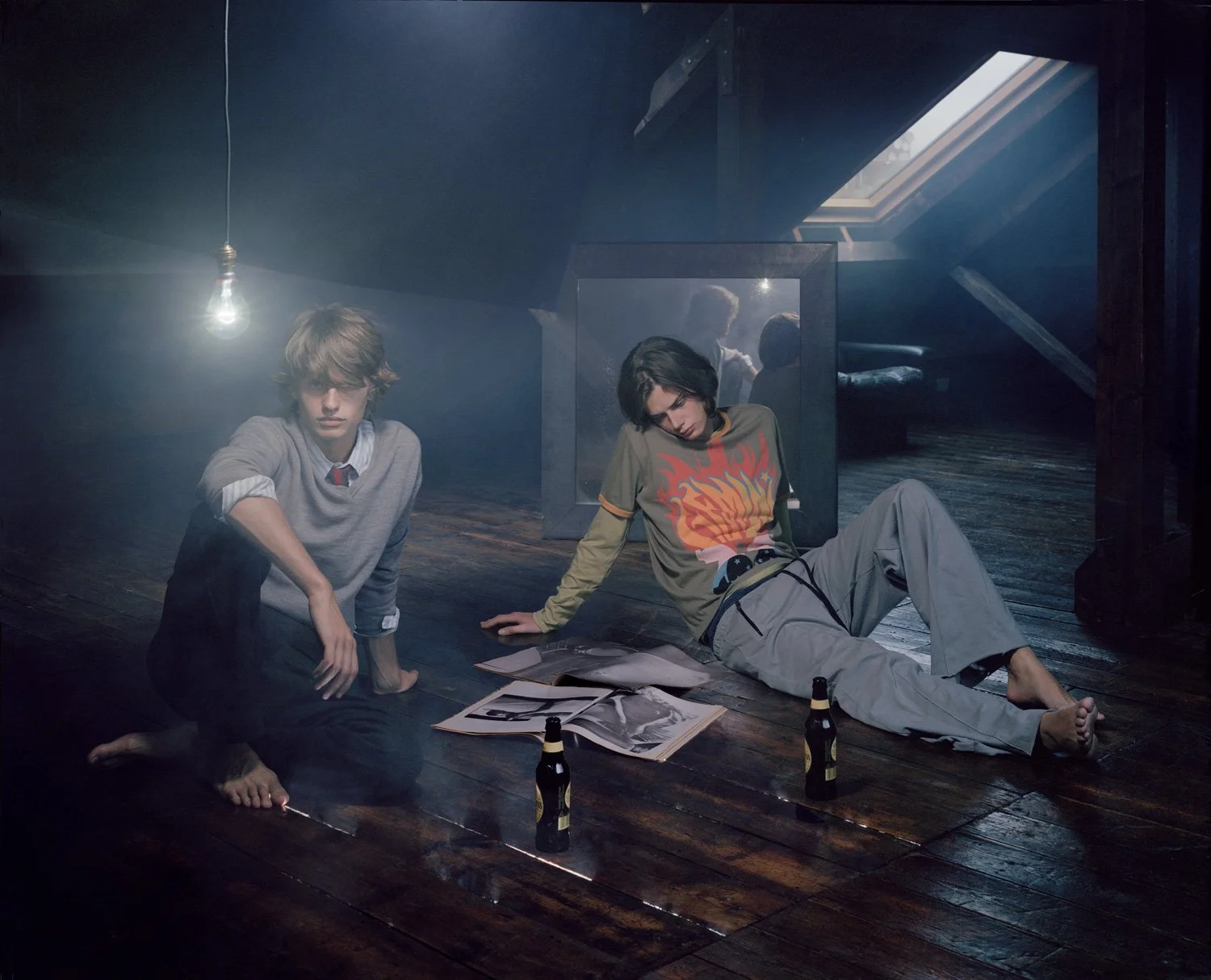 two guys sitting in a cool atmospheric attic reading magazines and drinking beer light streams through a skylight window